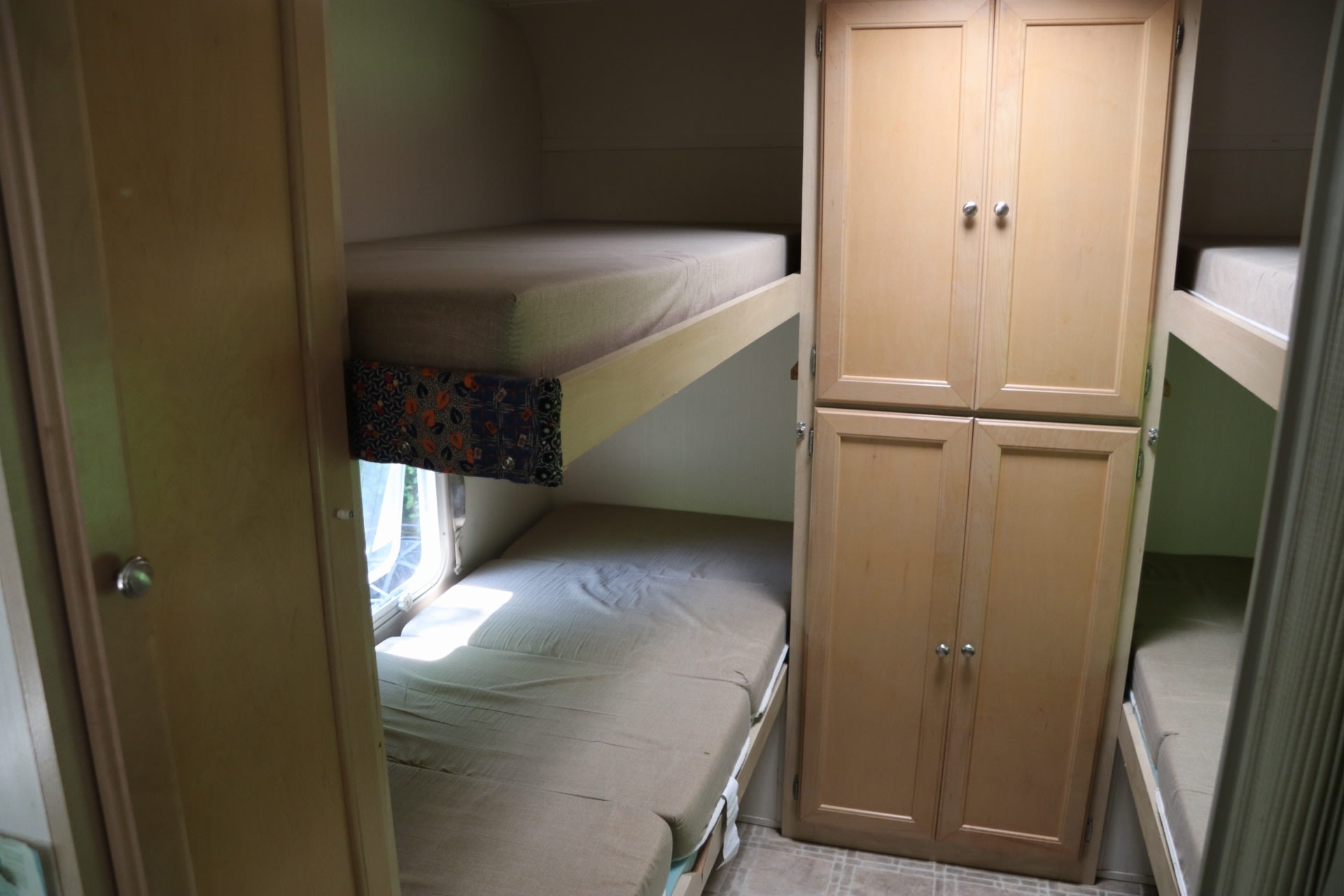 This RV rental interior features comfy stacked bunk beds with mattresses and wooden storage cabinets, perfect for adventures.. Forest River Surveyor 2003