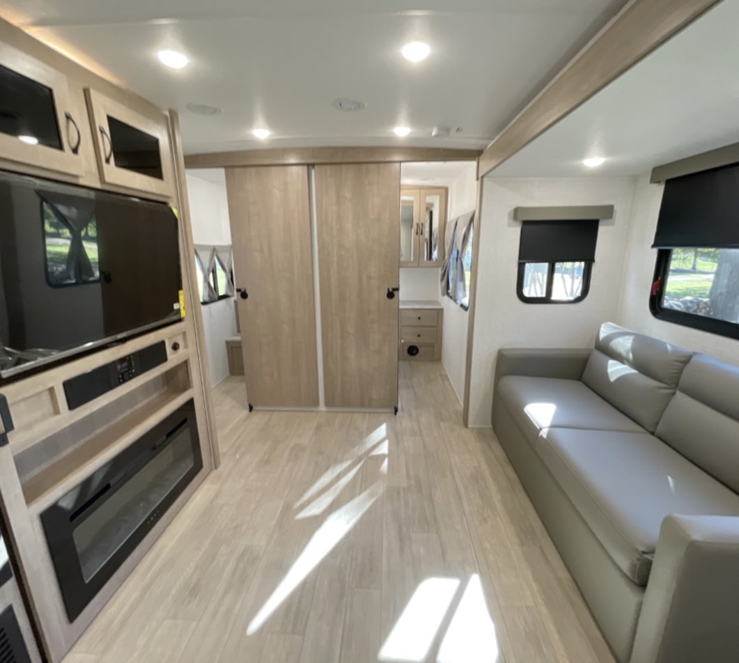 Modern RV rental with living space, gray sofa, TV/fireplace, and wood-look flooring. Ready for your next adventure.. Polamino Solaire 2025