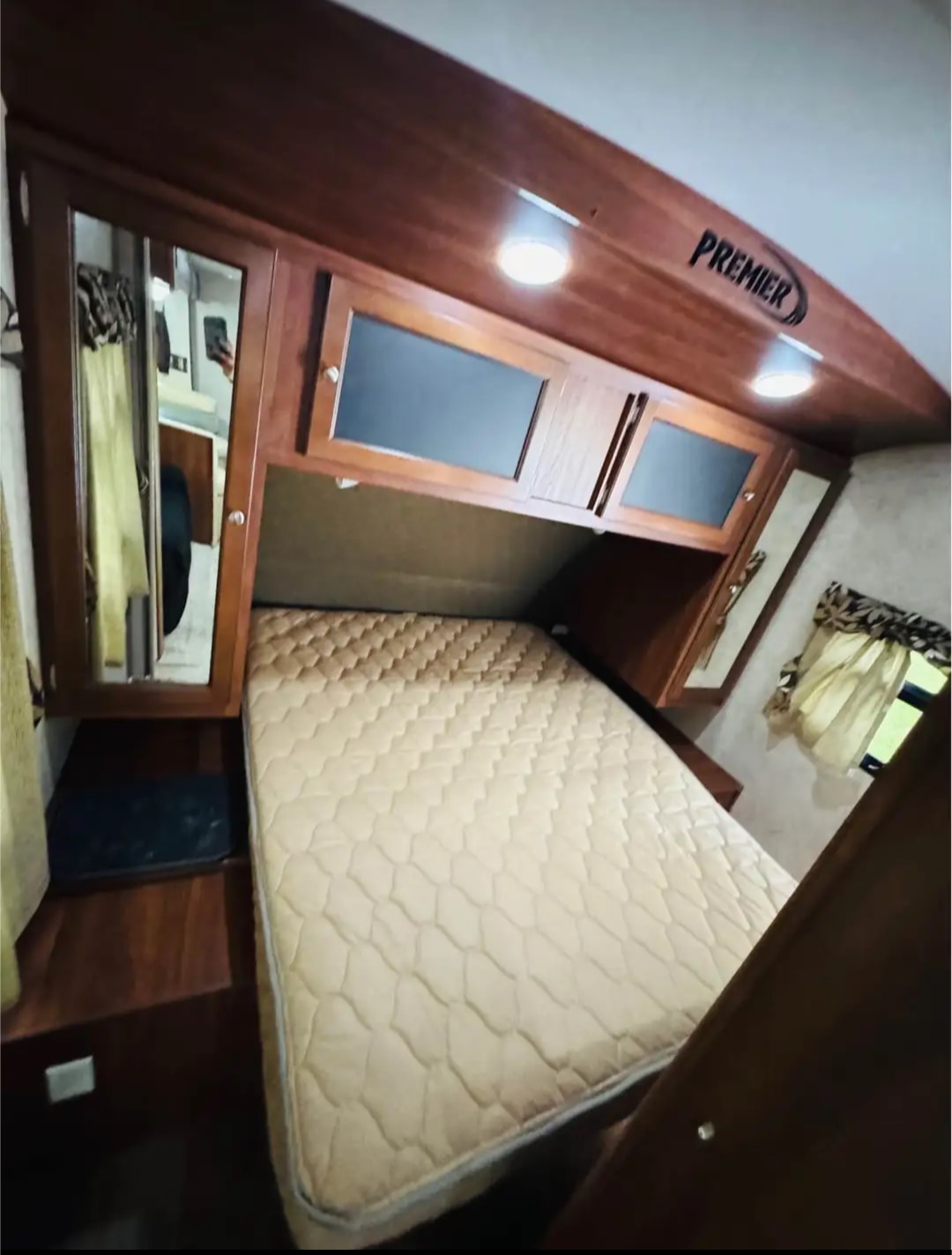 Cozy RV rental bedroom showing a mattress, wooden overhead Premier cabinets, and integrated lighting.. Keystone RV Bullet Premier Ultra 2013