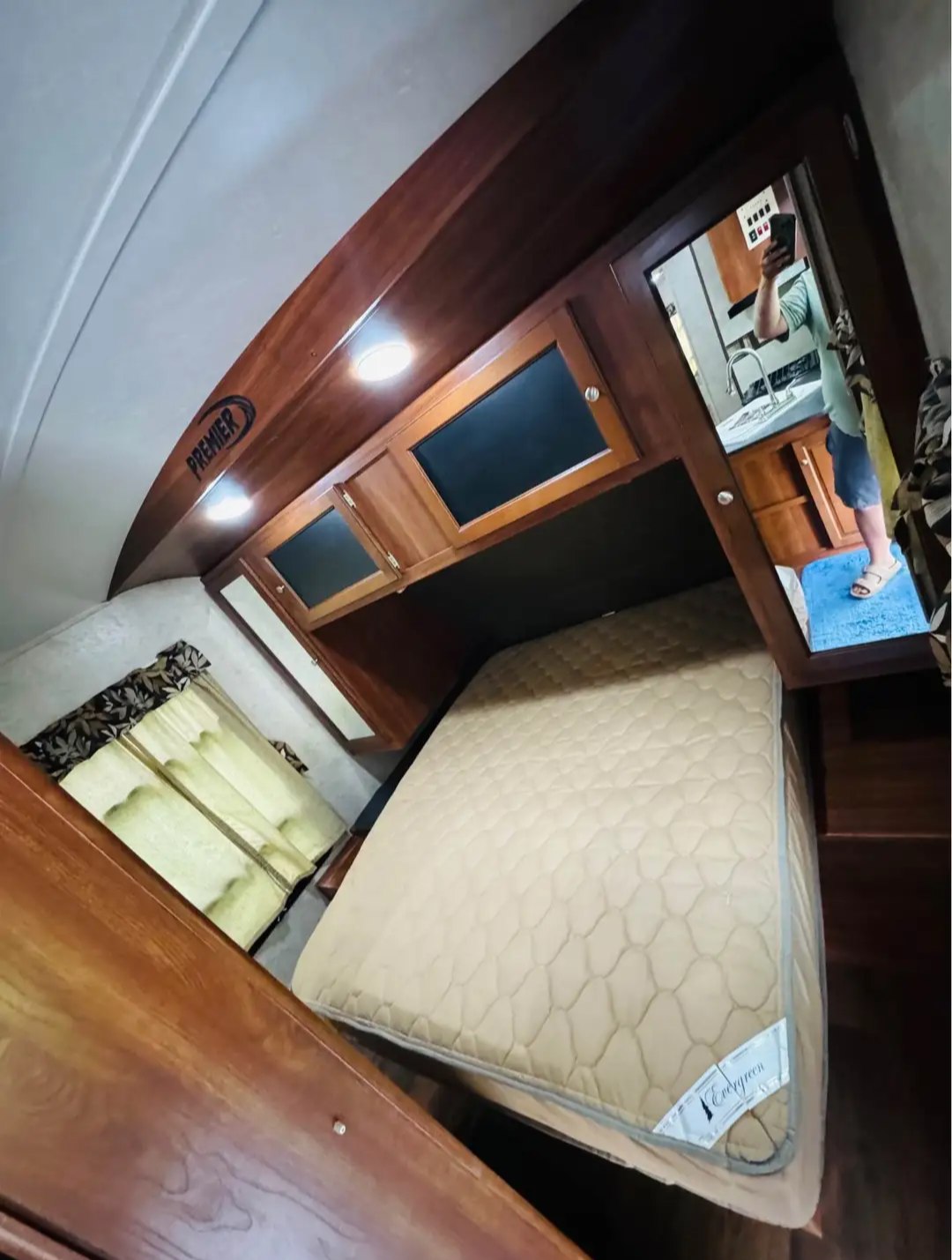 This RV rental interior features a compact bedroom with an "Evergreen" mattress, overhead cabinets, and a mirrored kitchen view.. Keystone RV Bullet Premier Ultra 2013