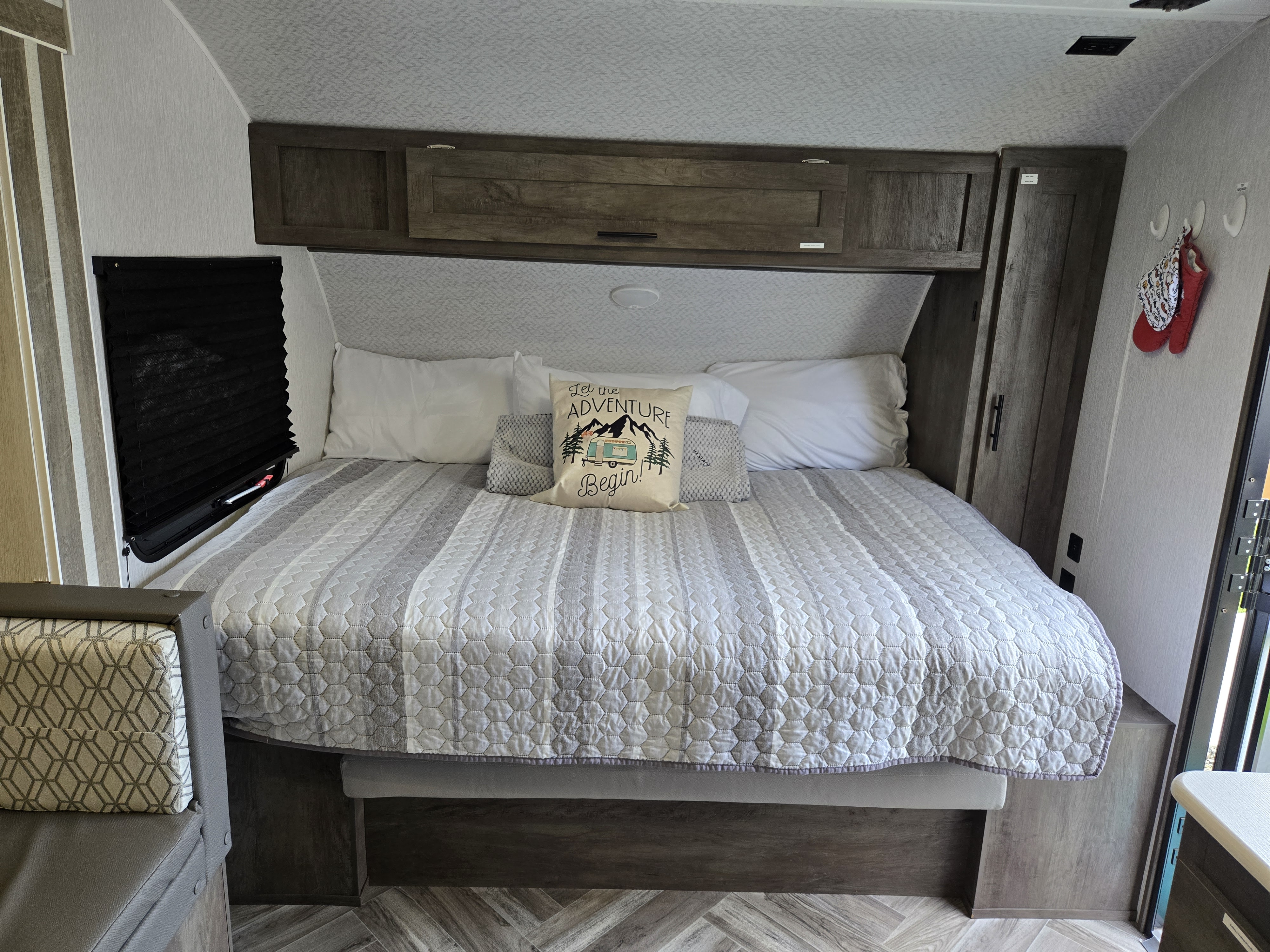 Inside an RV rental: a bright, inviting bedroom with a bed, patterned quilt, and "Let the Adventure Begin" pillow.. Forest River EVO 178B 2022