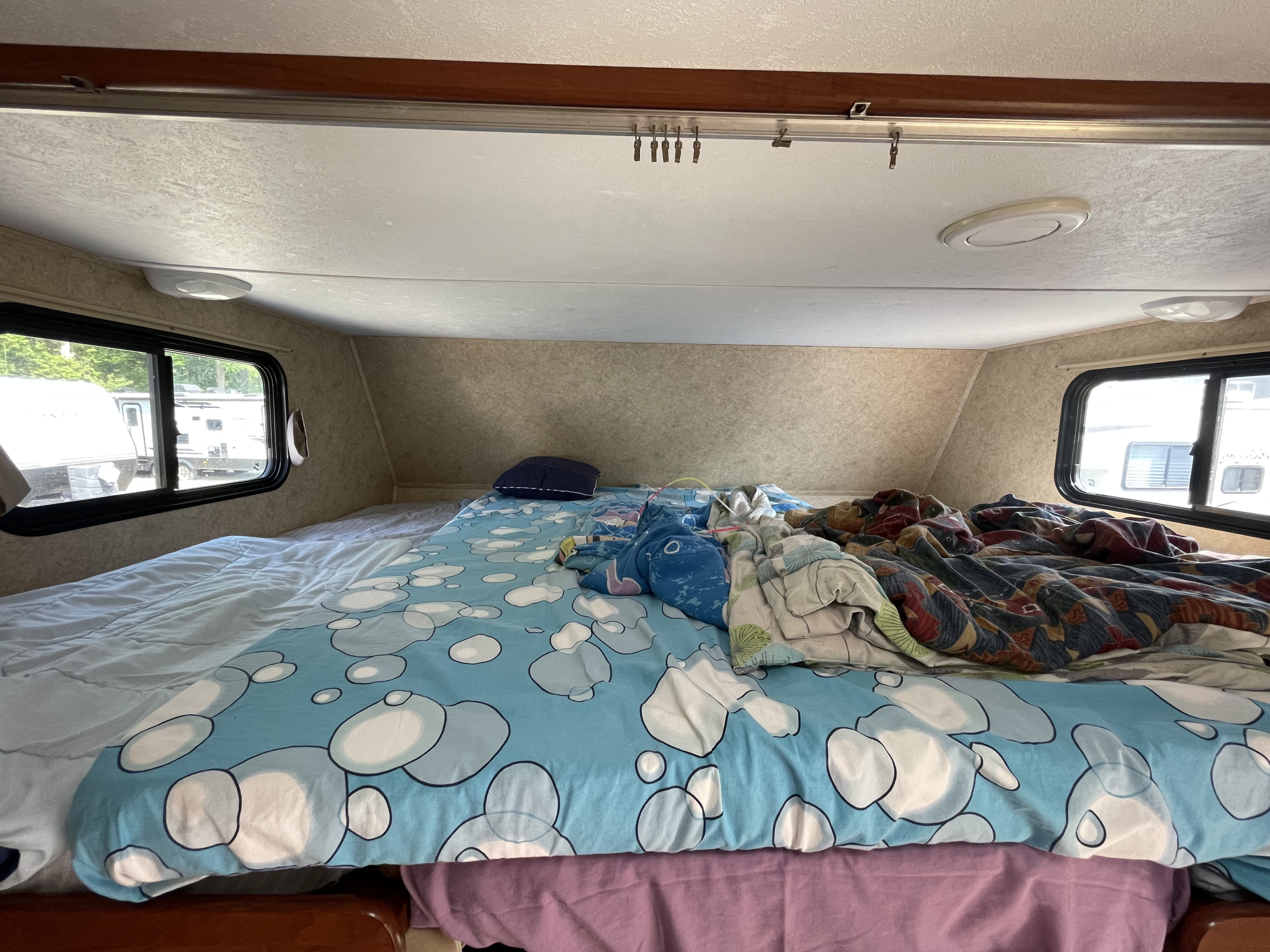 RV rental cozy bed with blue bubble pattern sheets and side windows. Ideal for a relaxing camping trip.. Forest River Sunseeker 2011