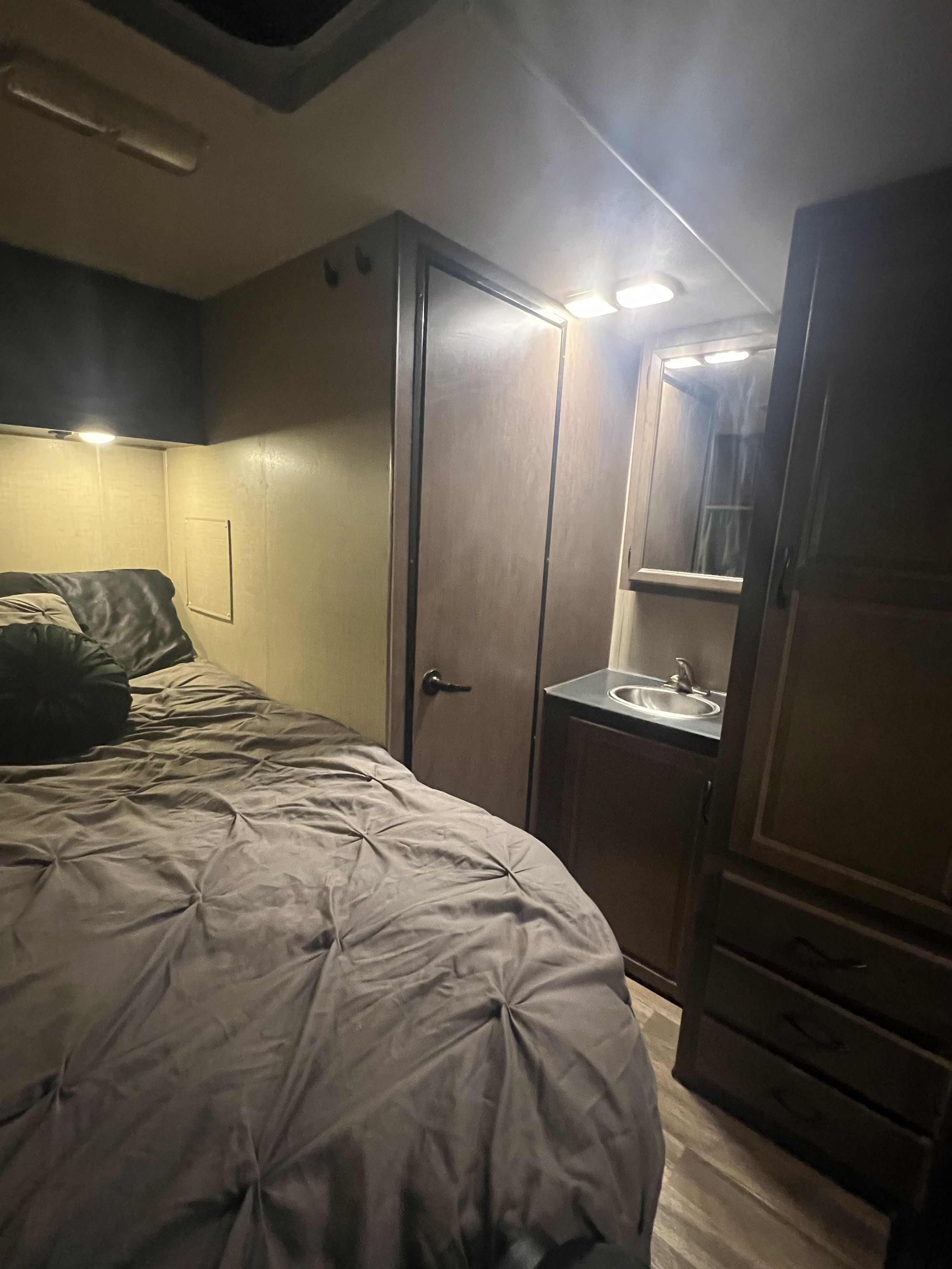 RV rental: Compact interior with a cozy bed, dark bedding, integrated sink/vanity, and built-in storage.. Thor Majestic 2018