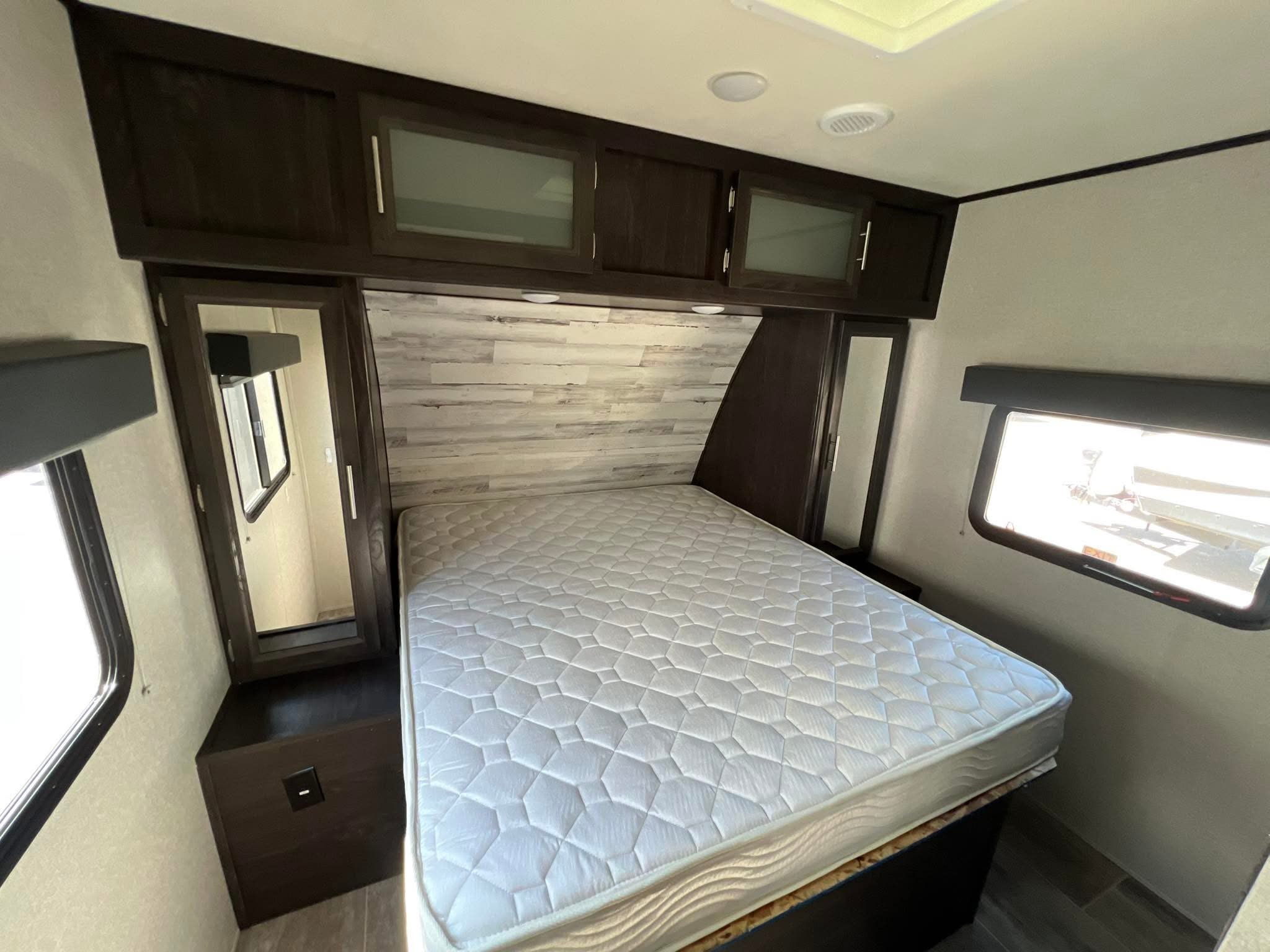 Comfortable RV rental bedroom featuring a queen bed, overhead cabinets, and mirrored closets. Ideal for travel.. Kodiak Ultralite 2019