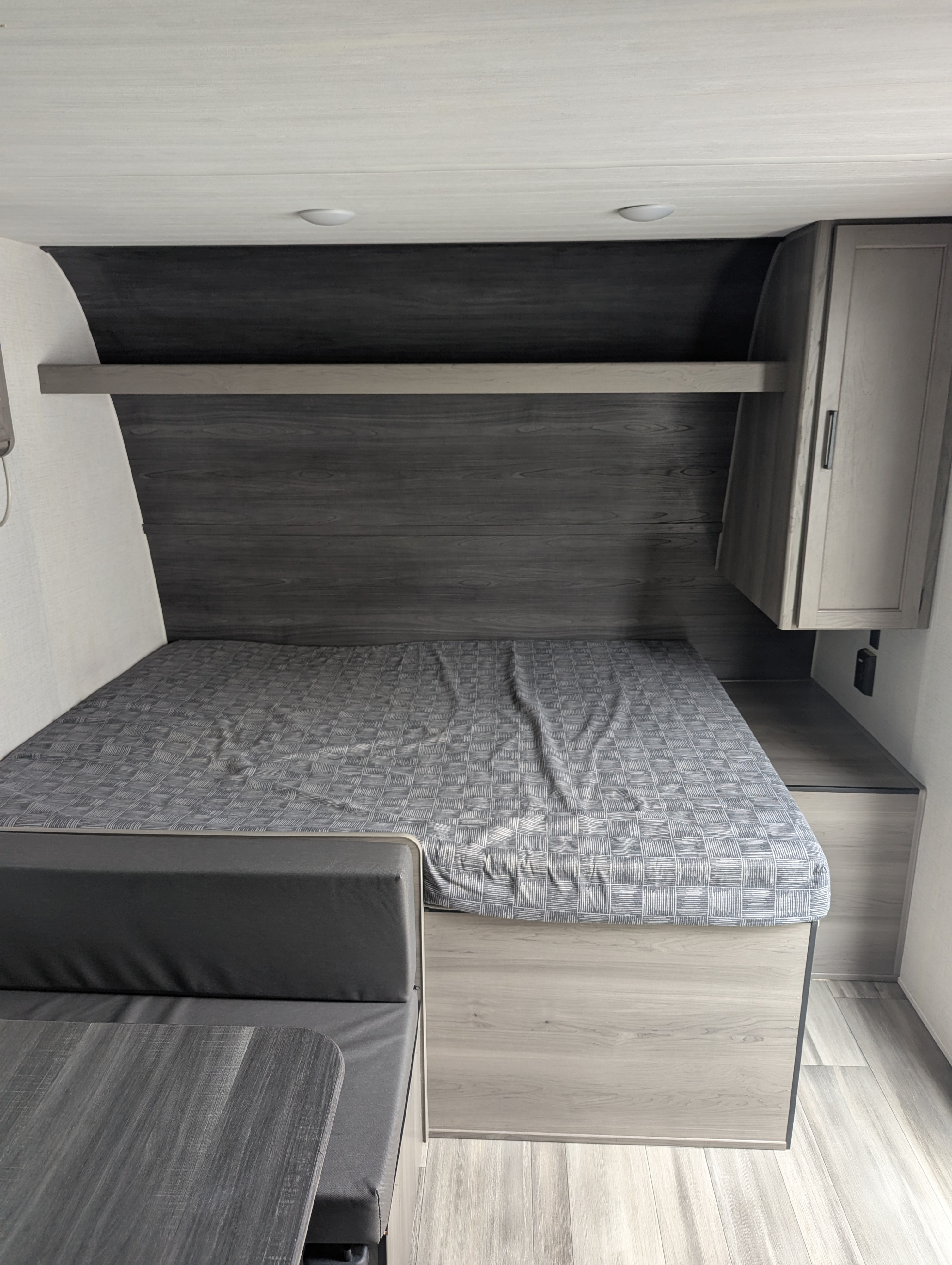 RV rental bedroom: Modern interior with comfy bed, overhead cabinet, and dinette seating.. Keystone Hideout 2024