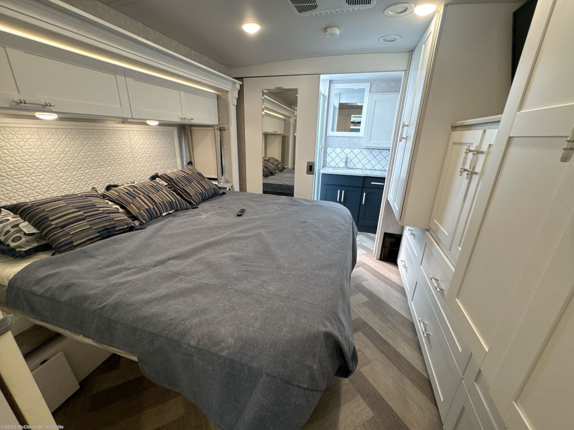 Experience comfort in this RV rental: bedroom featuring a large bed, stylish storage, and an accessible private bathroom.. Winnebago Adventurer 35f 2025