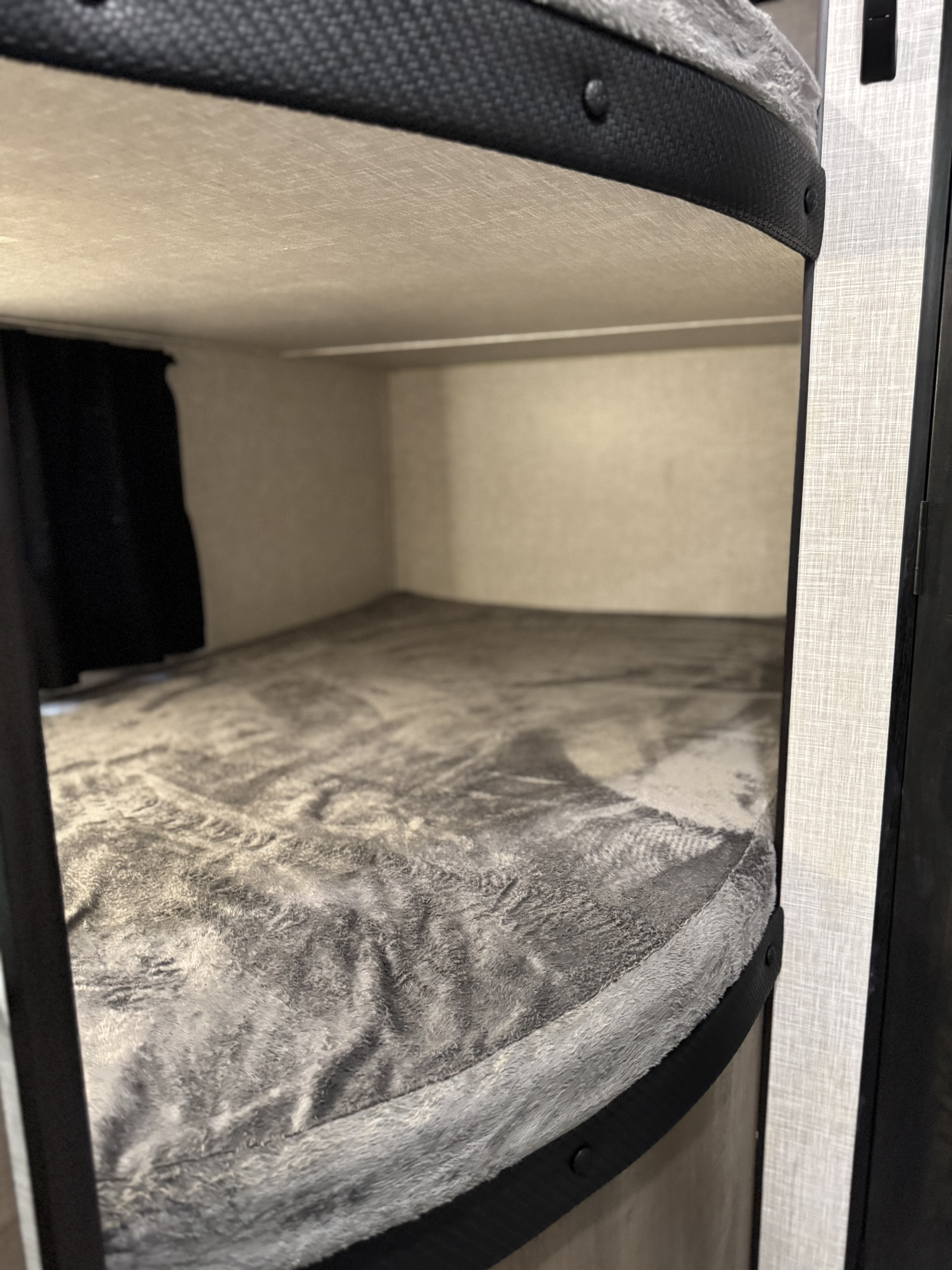 Cozy RV rental bunk bed with plush grey blanket inside a travel trailer, offering comfort for adventurers.. Jayco Jay Flight SLX 2024
