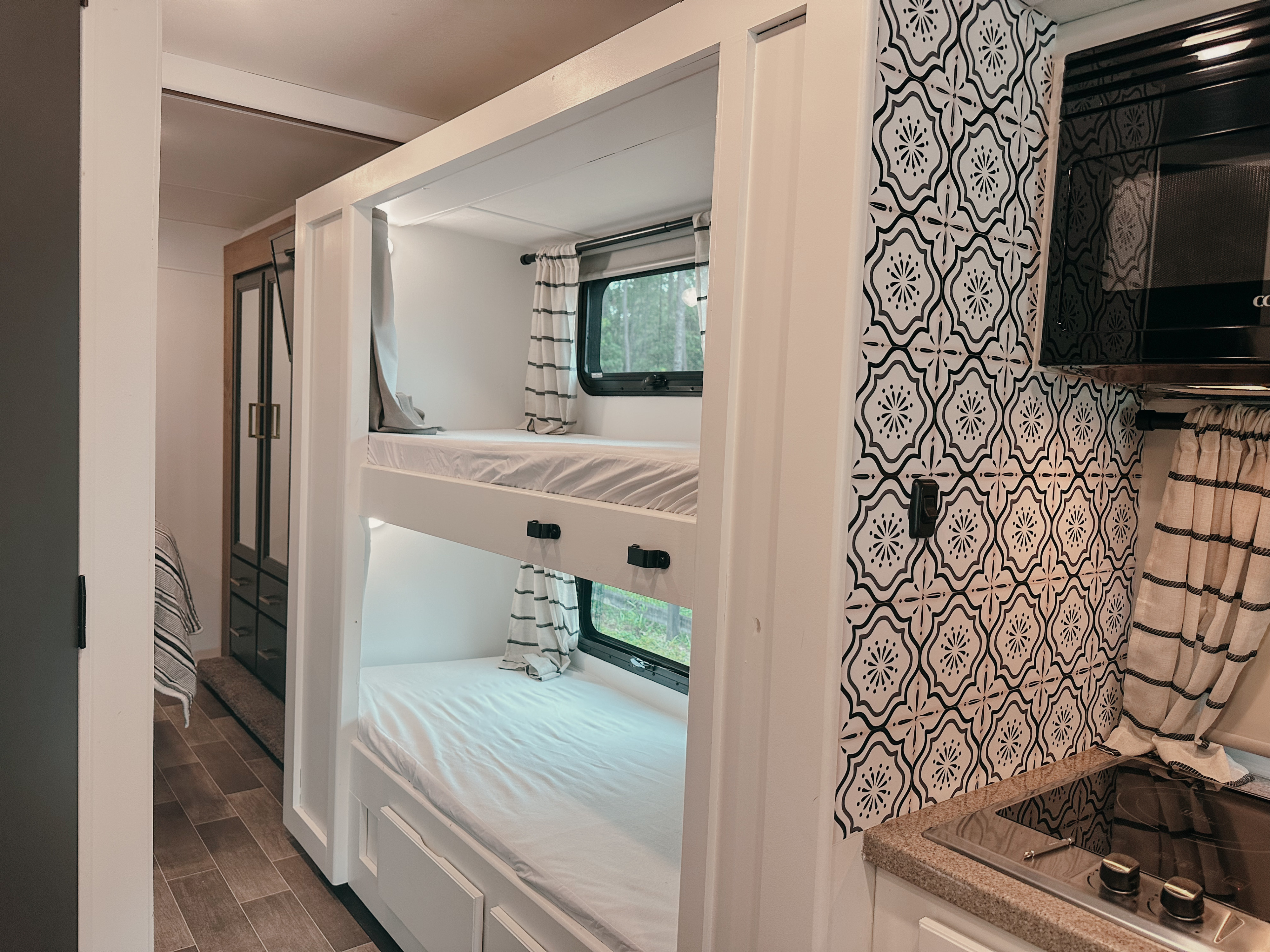 Chic RV rental interior showcasing cozy bunk beds, a stylish patterned kitchen backsplash, and modern amenities.. Thor Chateau 2022