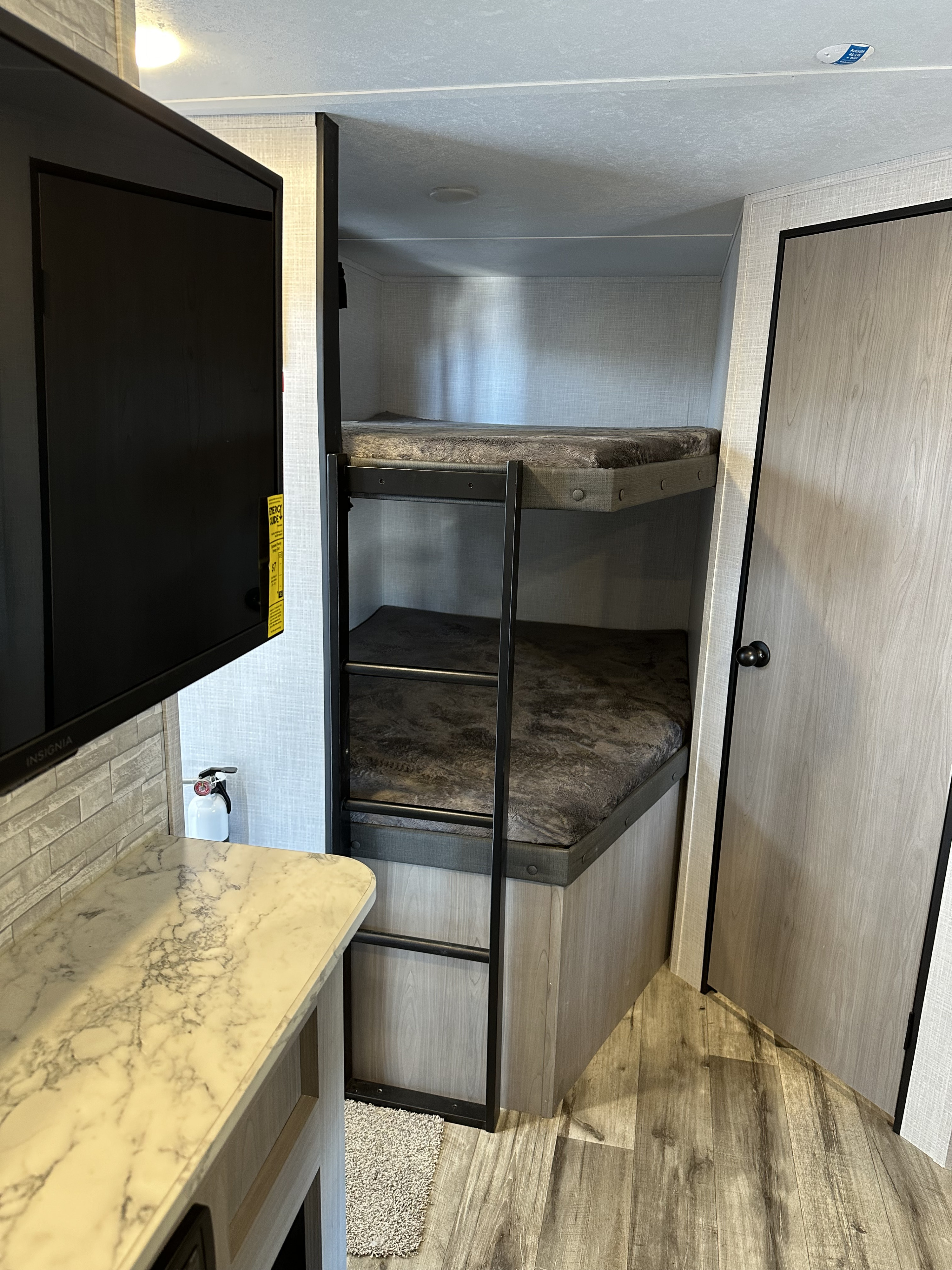 Cozy RV rental featuring bunk beds with ladder, TV, and modern counter. Ideal for group stays.. Coleman Dutchman Light 2023