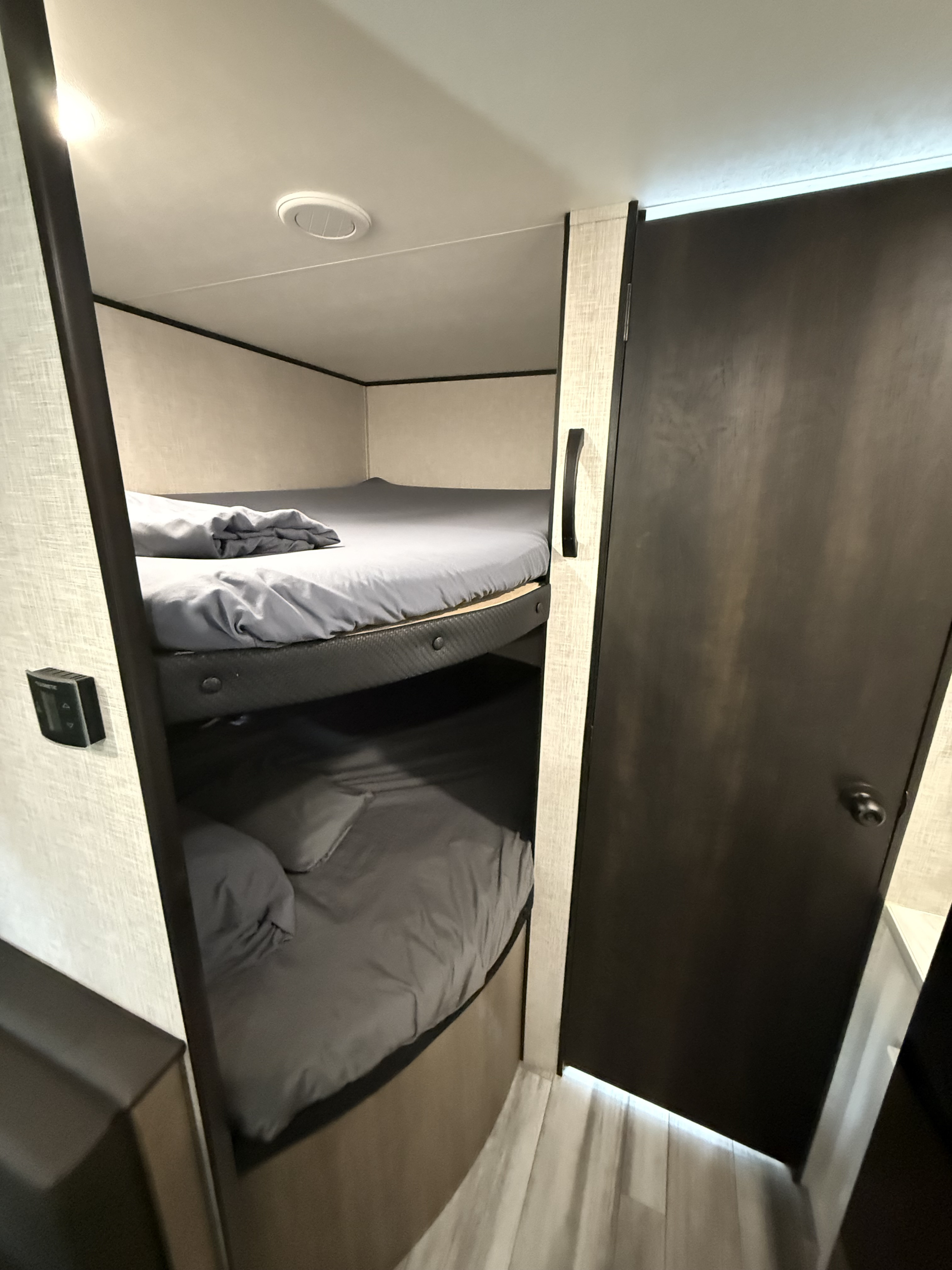 Cozy RV rental interior with grey-sheeted bunk beds, offering a practical sleeping space for your next adventure.. Jayco Jay Flight SLX 2024
