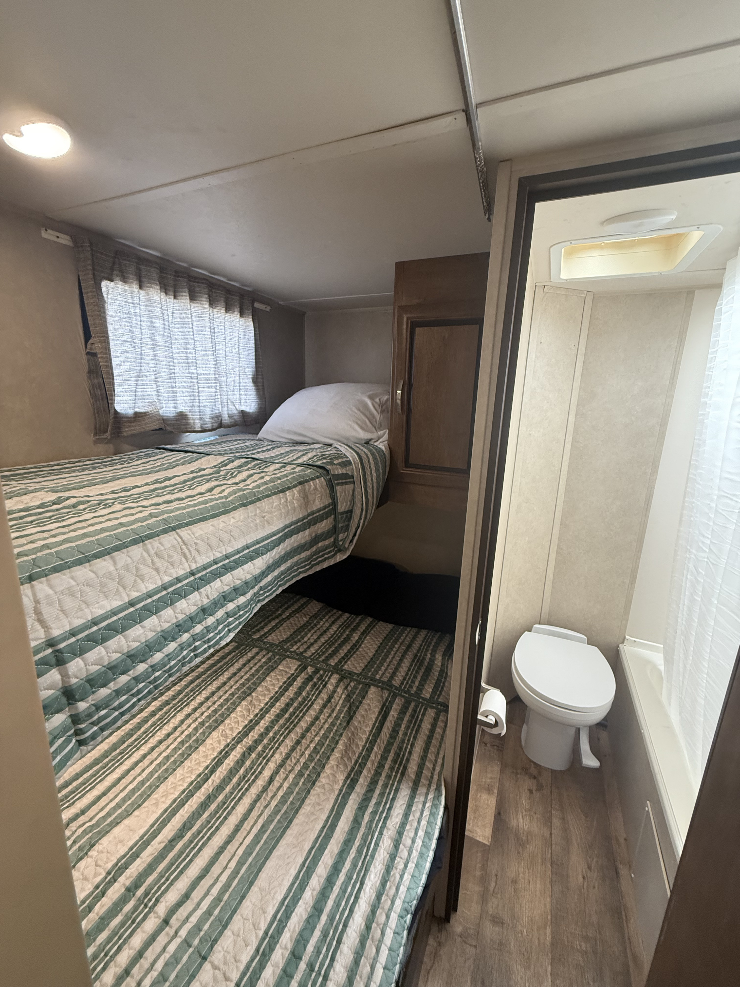 RV rental interior: two bunk beds with green/white striped bedding, and a compact bathroom with a toilet.. Forest River Salem Cruise Lite 2017