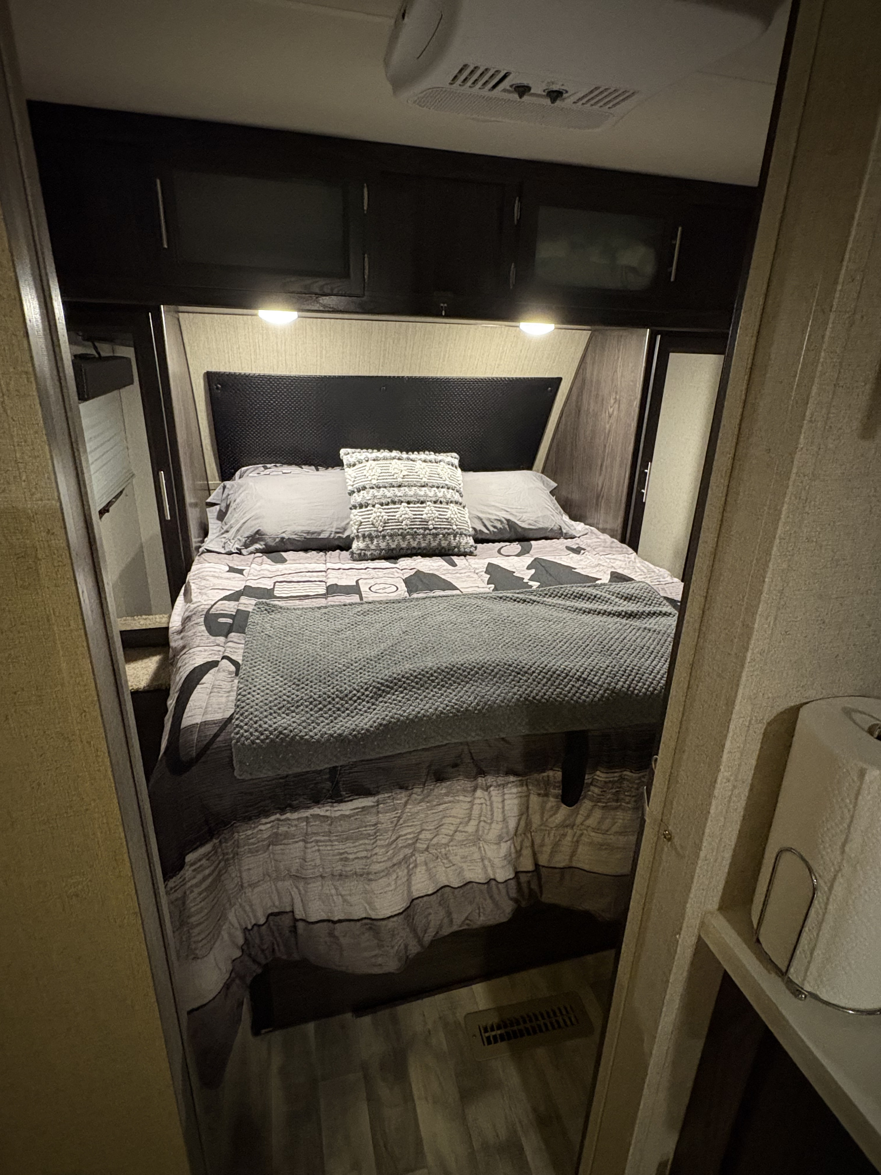 Cozy RV rental bedroom featuring a comfy bed, headboard, overhead storage, and an AC unit for a comfortable stay.. Dutchmen Kodiak Ultra Lite 2019