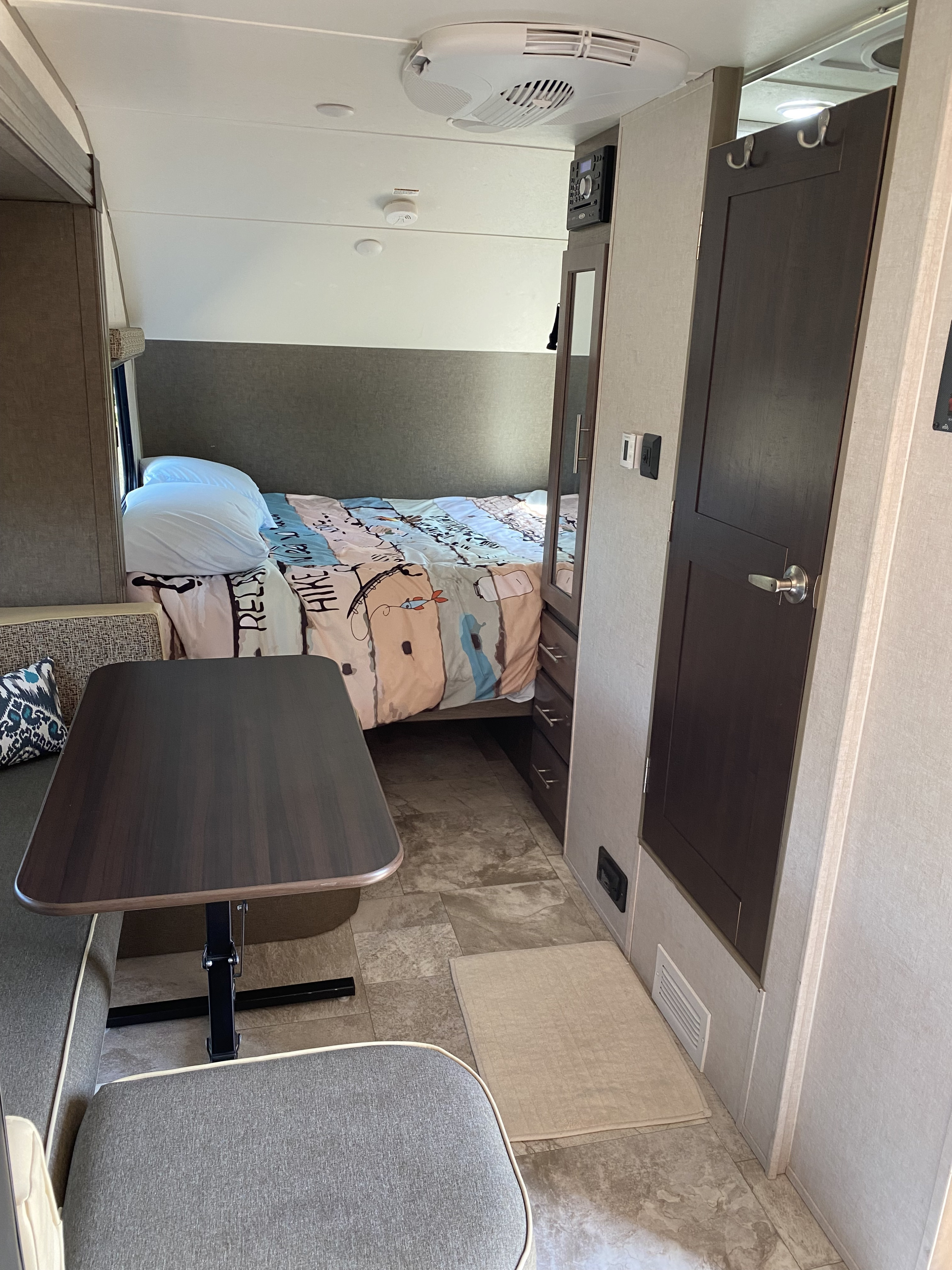 RV rental interior: a bed with colorful comforter, dinette, and wardrobe create a compact, functional living space.. R-Pod Hood River Edition 2018