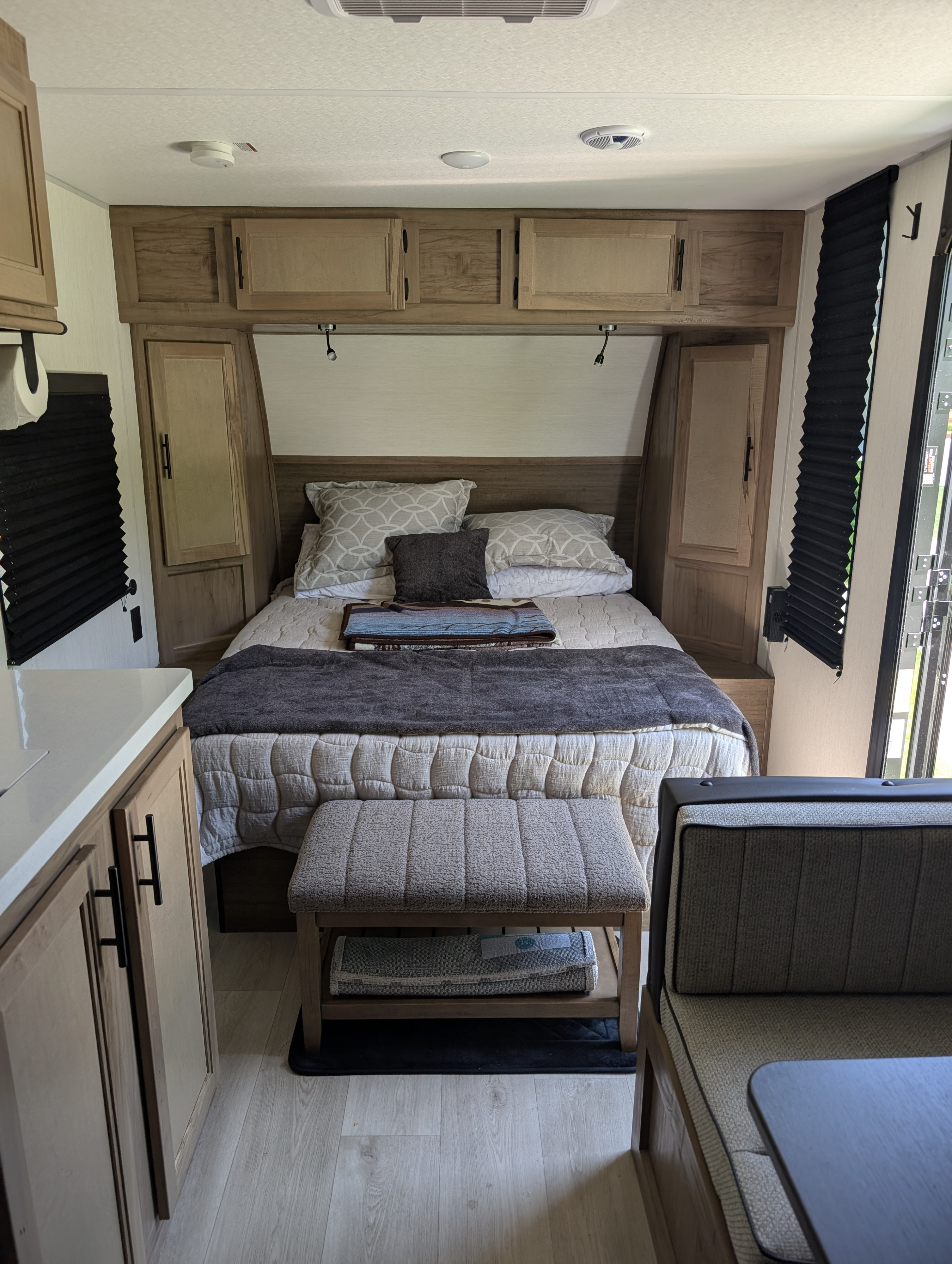 Inside a modern RV rental: comfortable bedroom with overhead cabinets, lighting, and cozy decor.. Forest River 16FQBLW 2025