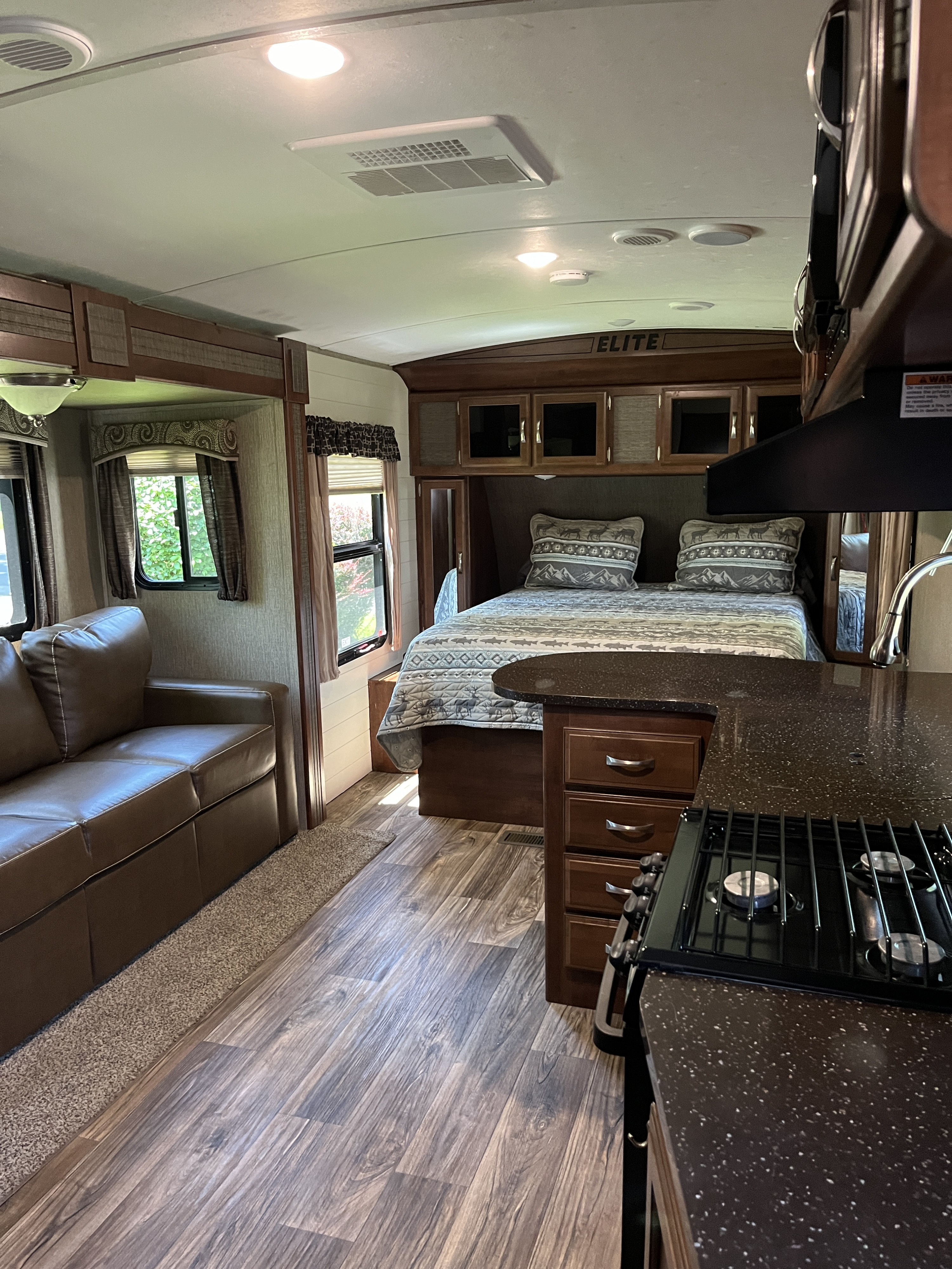 Spacious RV rental interior featuring a living area with couch, full kitchen, and comfortable bedroom with bed.. Keystone RV Passport Elite 2017