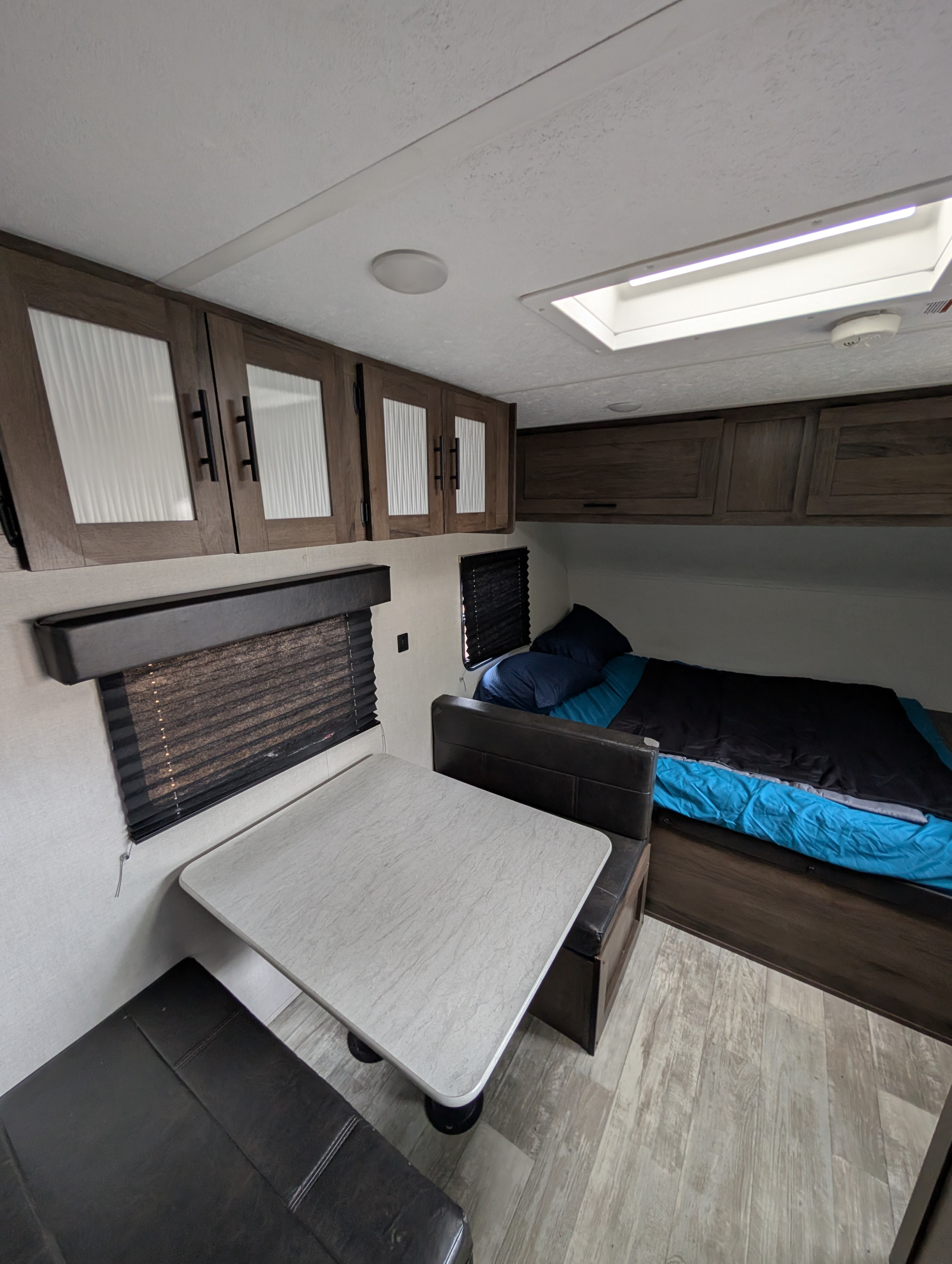Cozy RV rental interior featuring a dinette table with benches, overhead cabinets, and a compact bed area.. Avenger LT 2021
