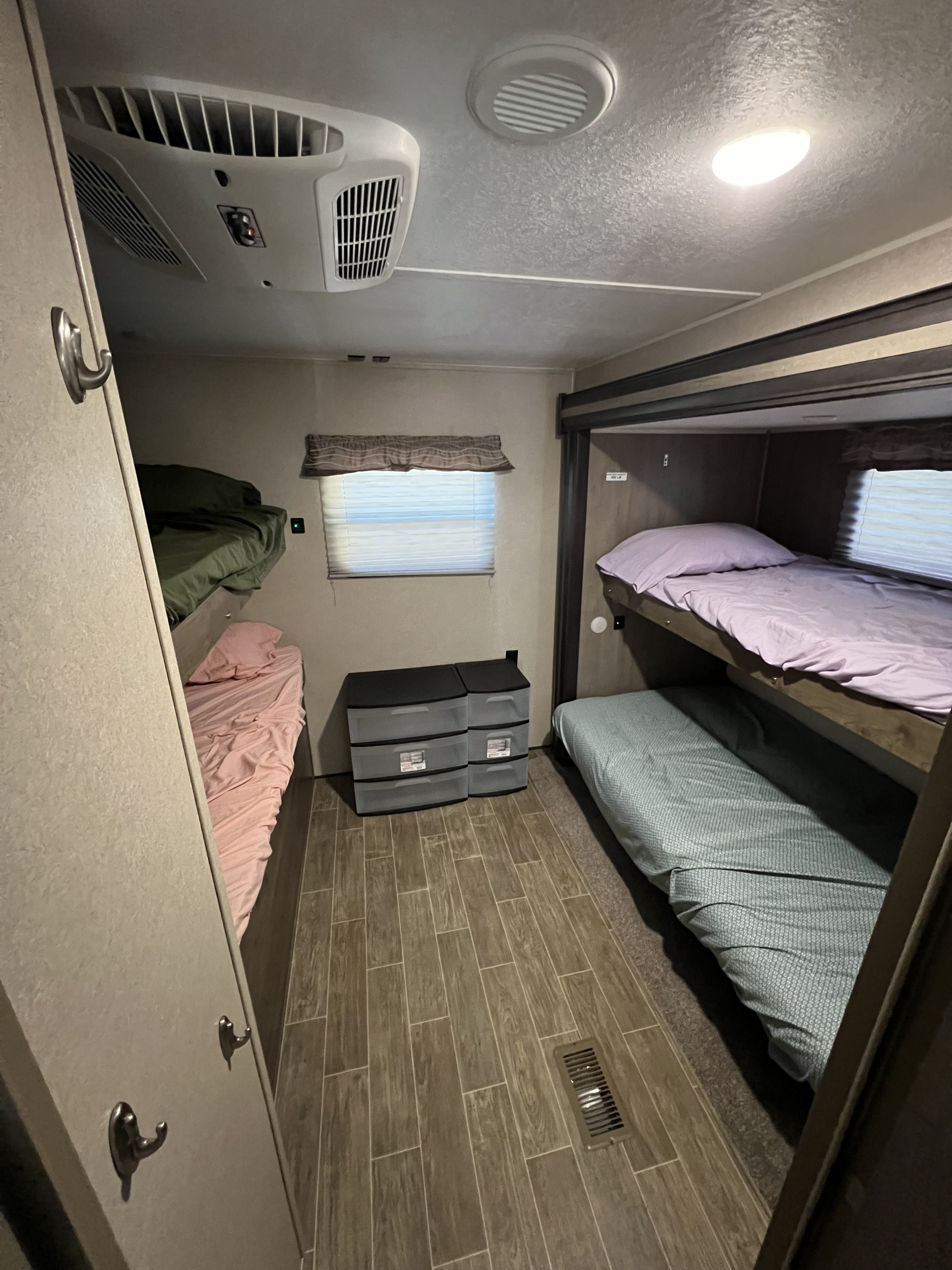Inside an RV rental: a bunk room with comfortable beds, ceiling AC, storage bins, and tiled floor for a cozy stay.. Forest River Palomino Puma 2020