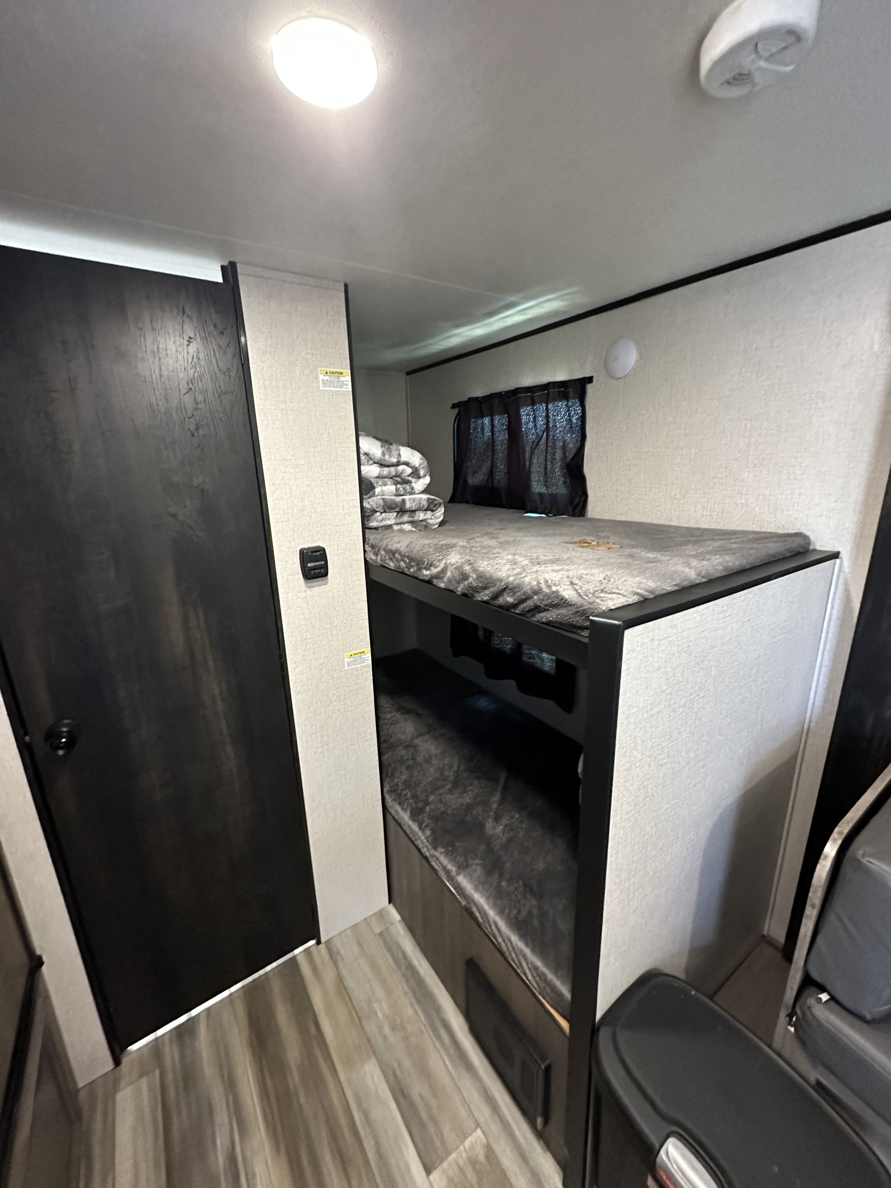 RV rental: Cozy interior with bunk beds, window, and wood floor. Features a black door & control panel for easy living.. Starcraft Autumn Ridge 2022