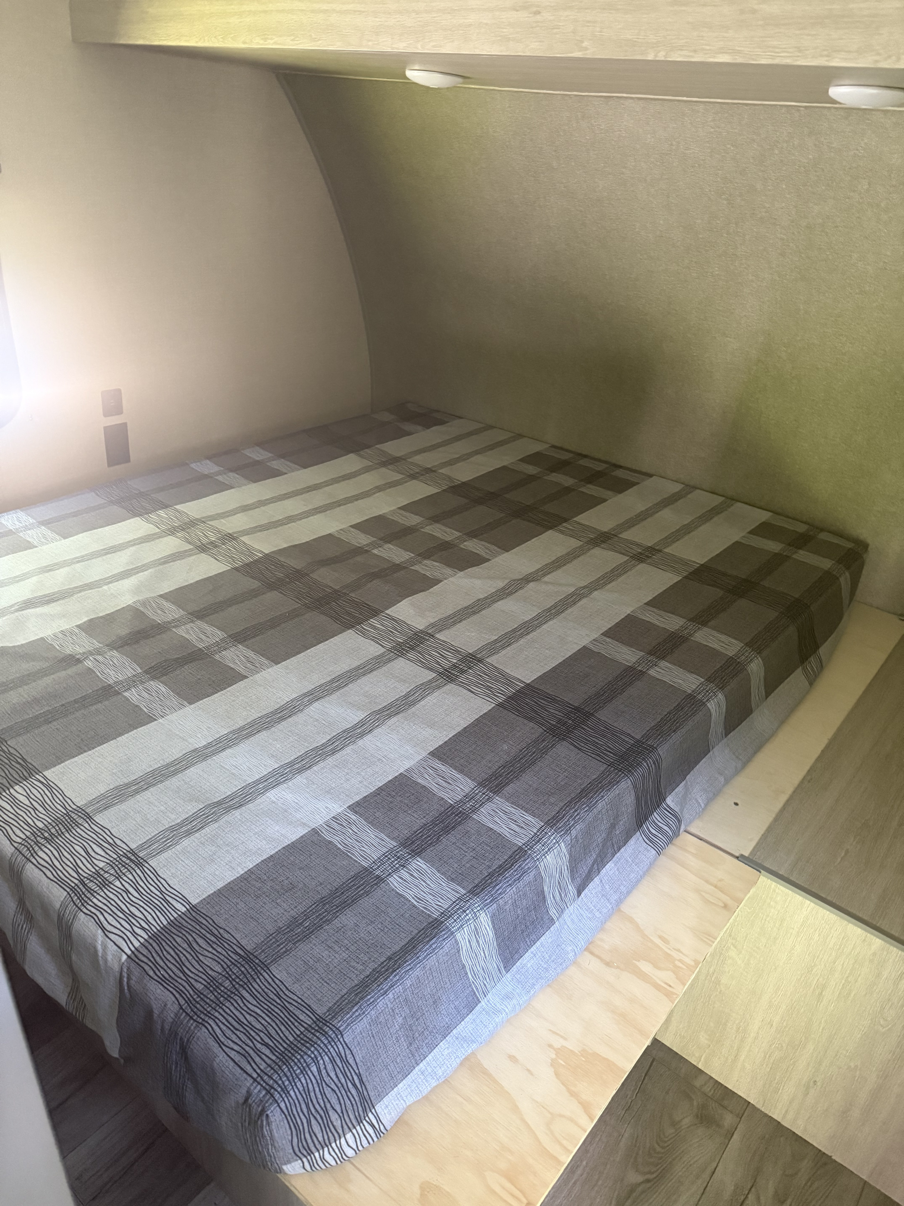 Inside an RV rental: a comfy sleeping area with a gray plaid mattress, wall outlets, and overhead lights for a cozy stay.. Coachmen 2022 Coachmen Catalina 28BHS 2022