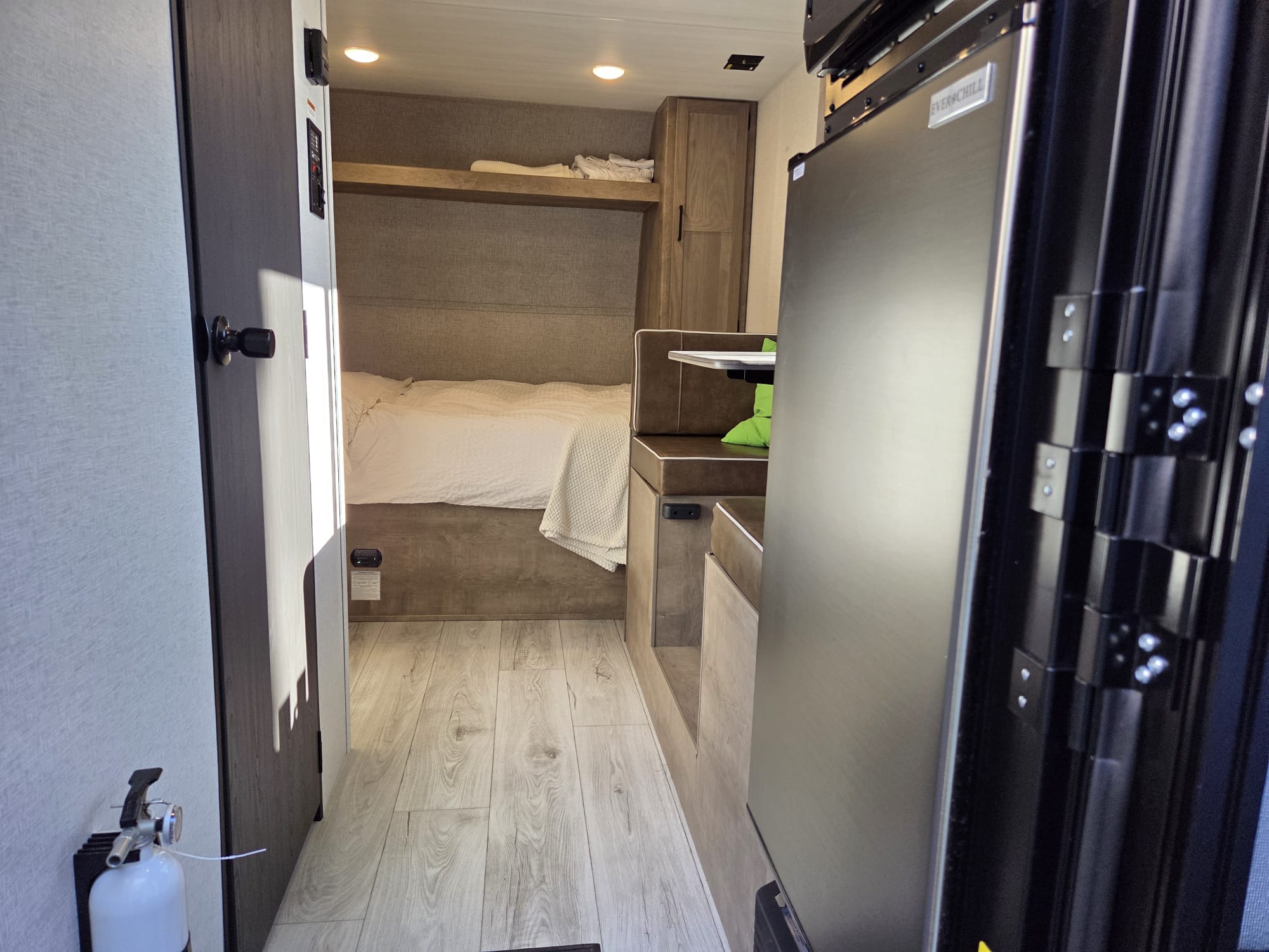 This inviting RV rental interior features a cozy bed, bunk, dinette, & modern refrigerator, perfect for camper adventures.. Keystone Springdale 1400RE 2025