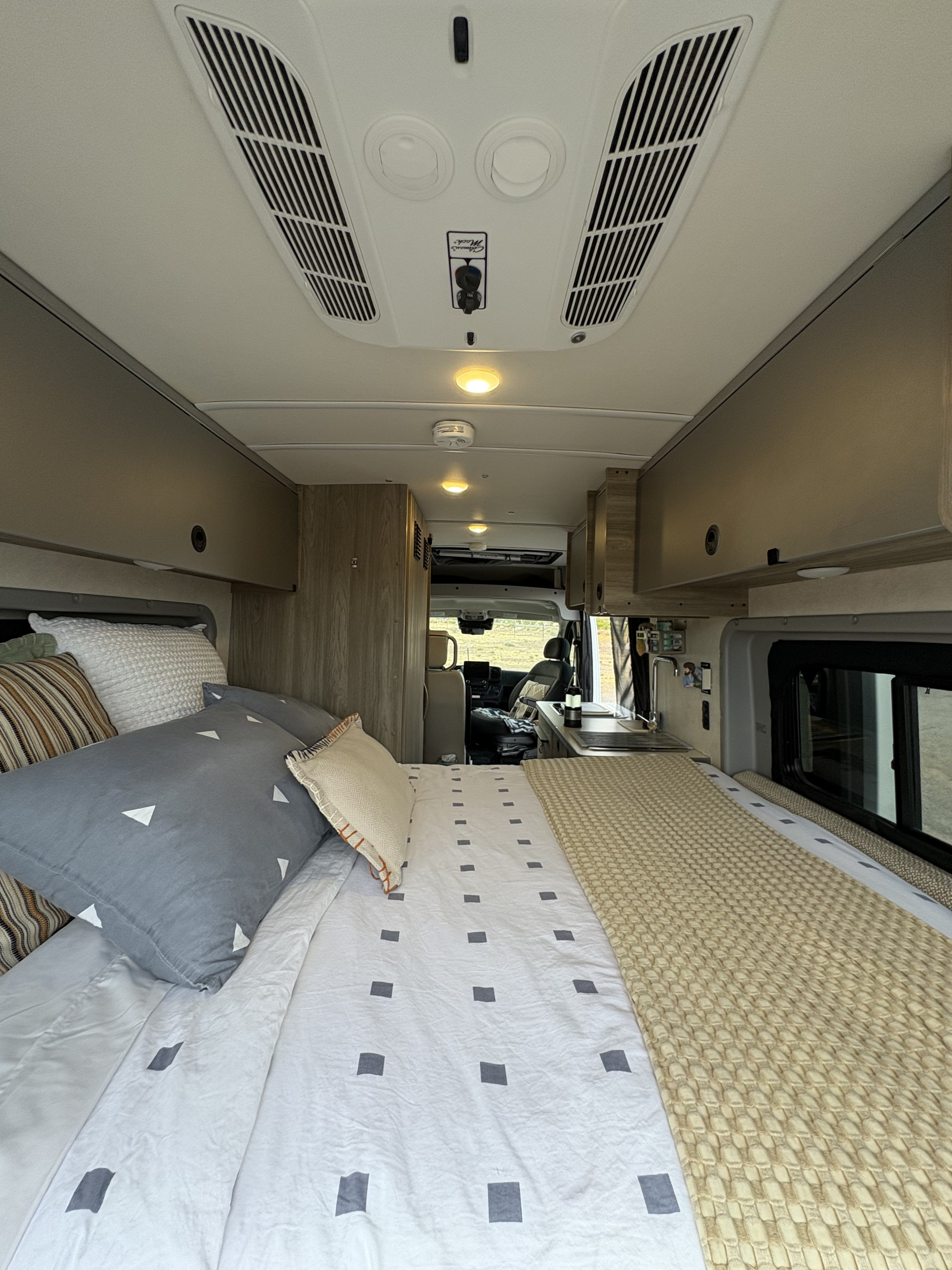 RV rental's inviting interior: features a comfy bed, kitchenette, and driver's cabin with an outdoor view.. Winnebago Winnebago Solis 59PX Dodge Ram 2023