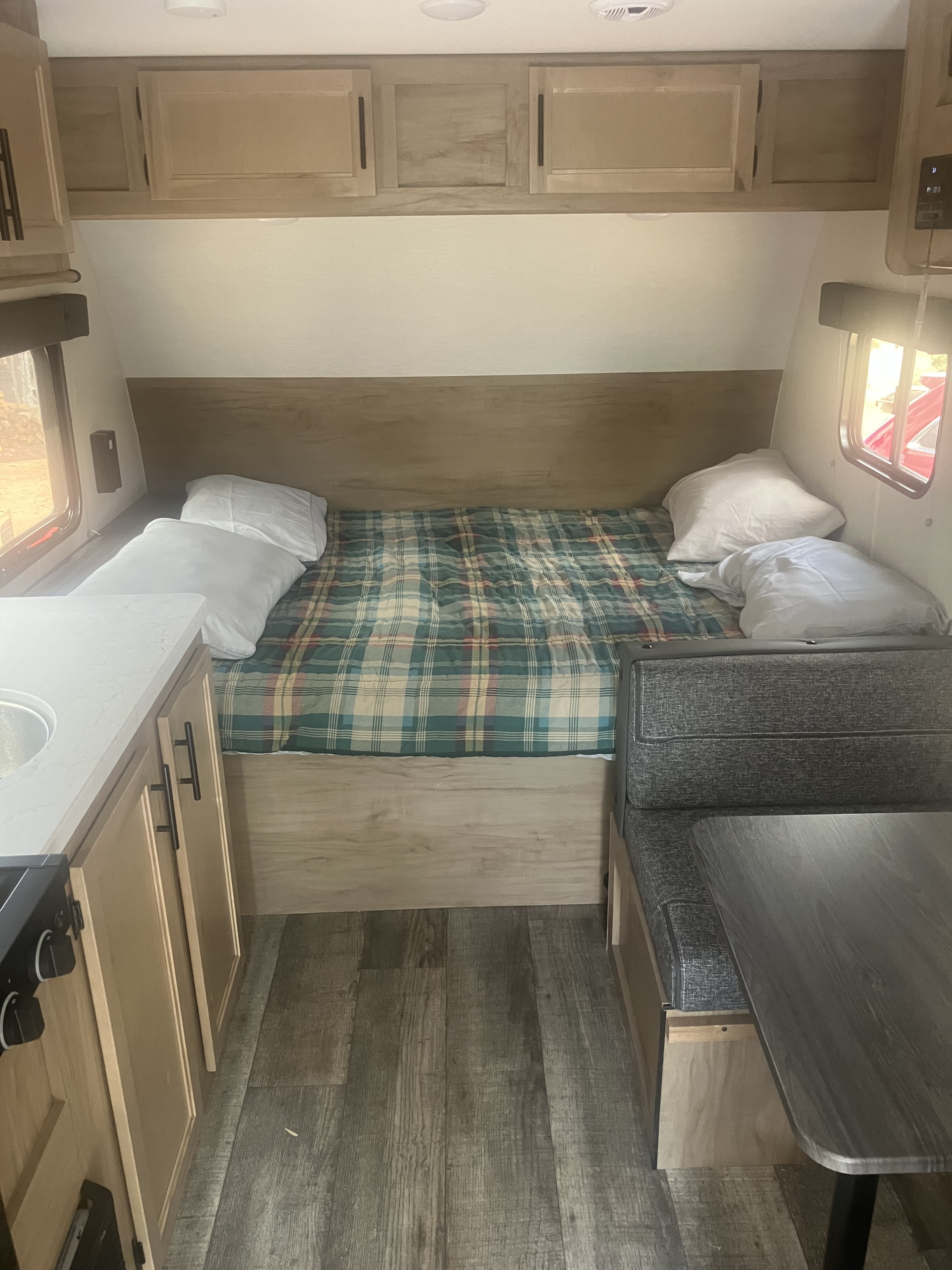 Compact RV rental interior featuring a cozy bed, kitchen area with sink, and a dinette with table.. Forest River Wolf Pup 2024