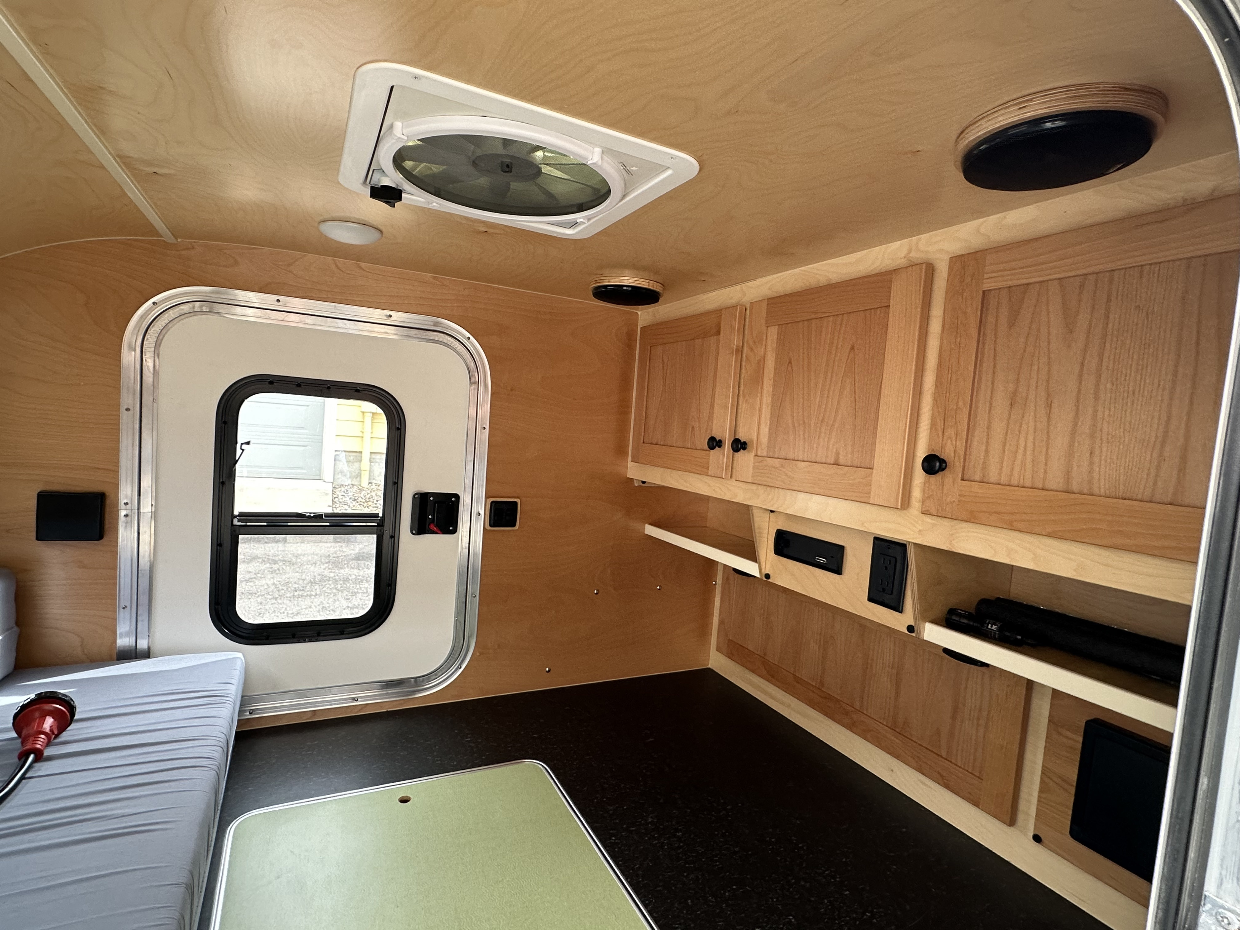 Clean, modern RV rental interior featuring light wood walls, storage cabinets, and comfortable sleeping area.. Aero Teardrops Steel HC 2021