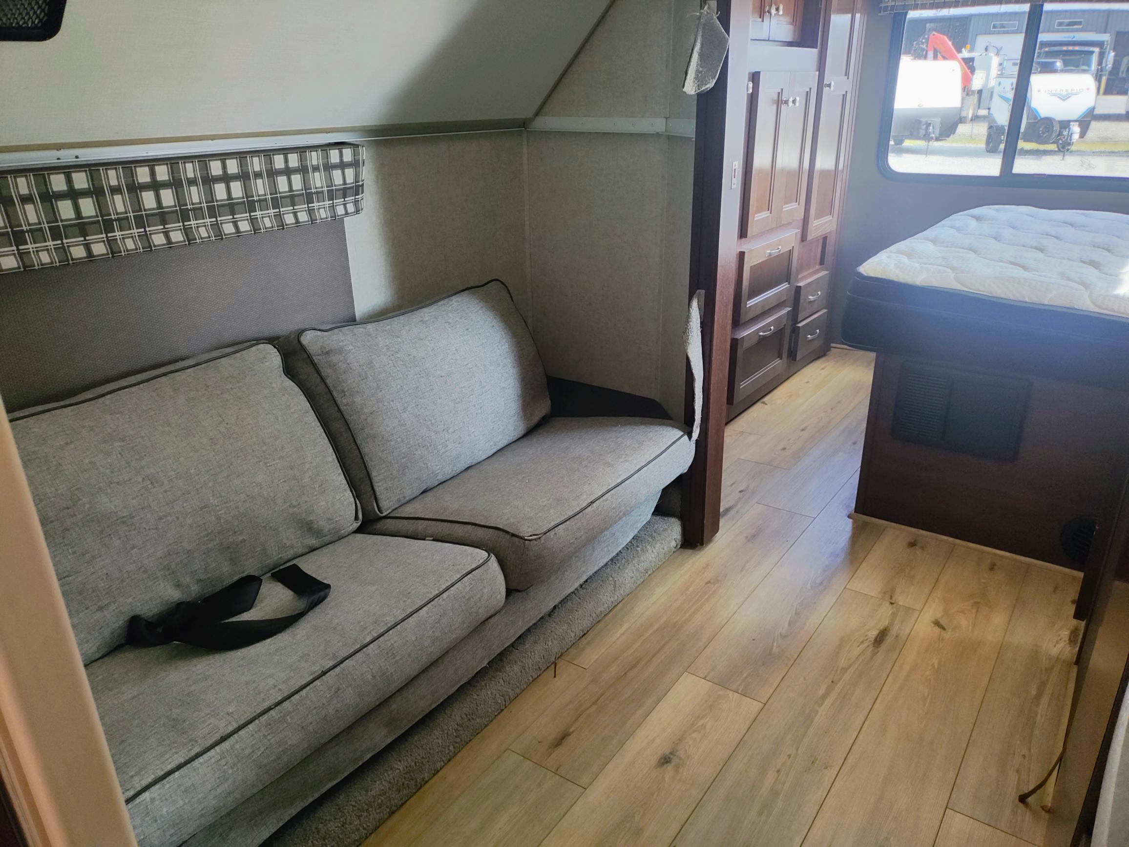 RV rental interior with gray sofa, wood cabinets, and bed. Cozy, functional space for your travel adventures.. Forest River Sunseeker LE 2020