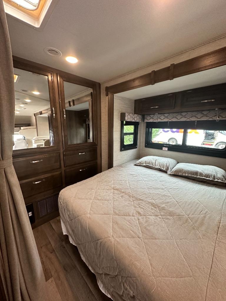RV rental: Bright bedroom with queen bed, dark wood storage, mirrored wardrobe, and natural light from skylight.. Jayco Redhawk 2021