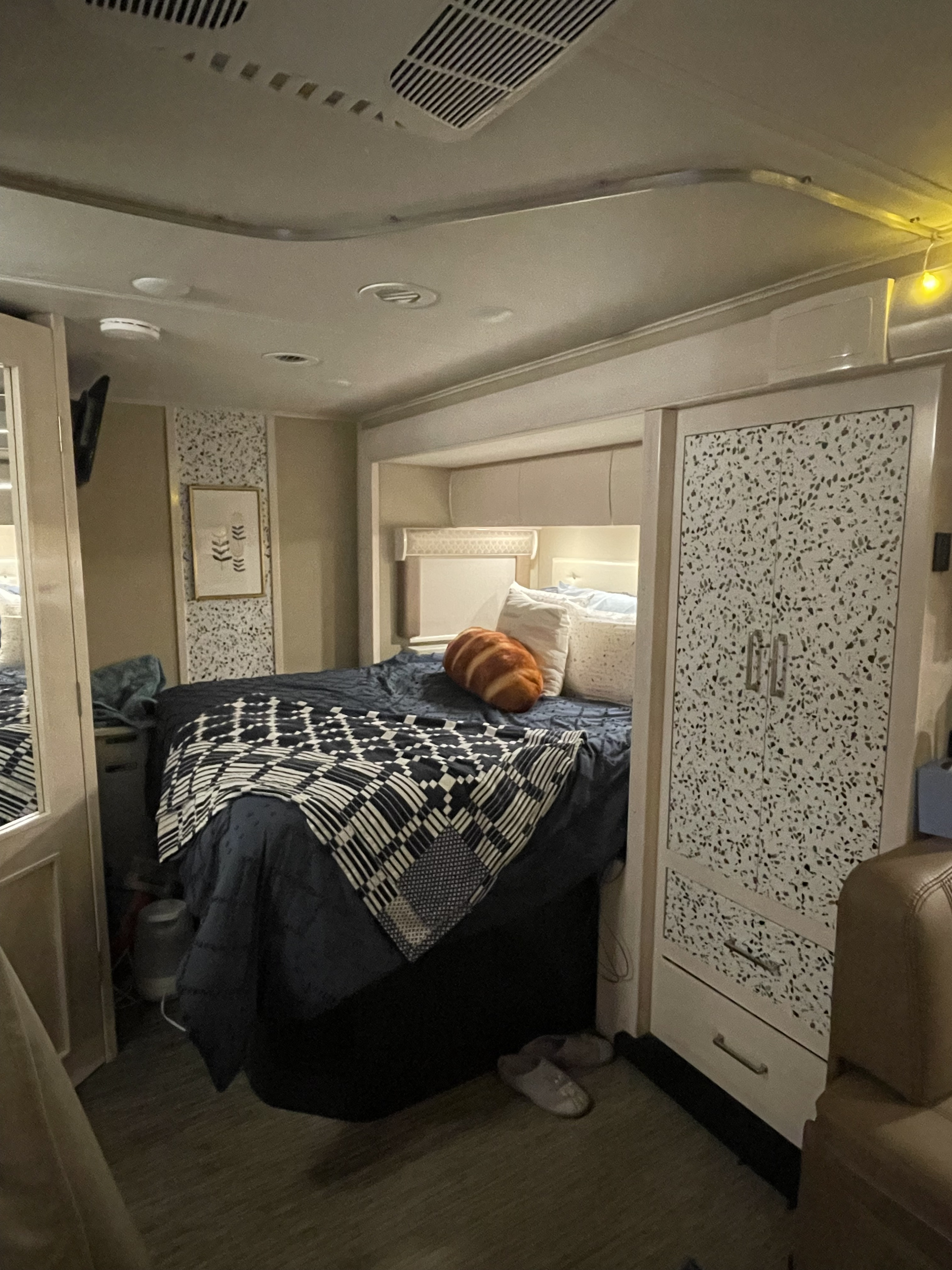 Cozy RV rental bedroom with a comfortable bed, overhead storage, and a stylish speckled cabinet.. Renegade Custom Coaches Vienna 2021
