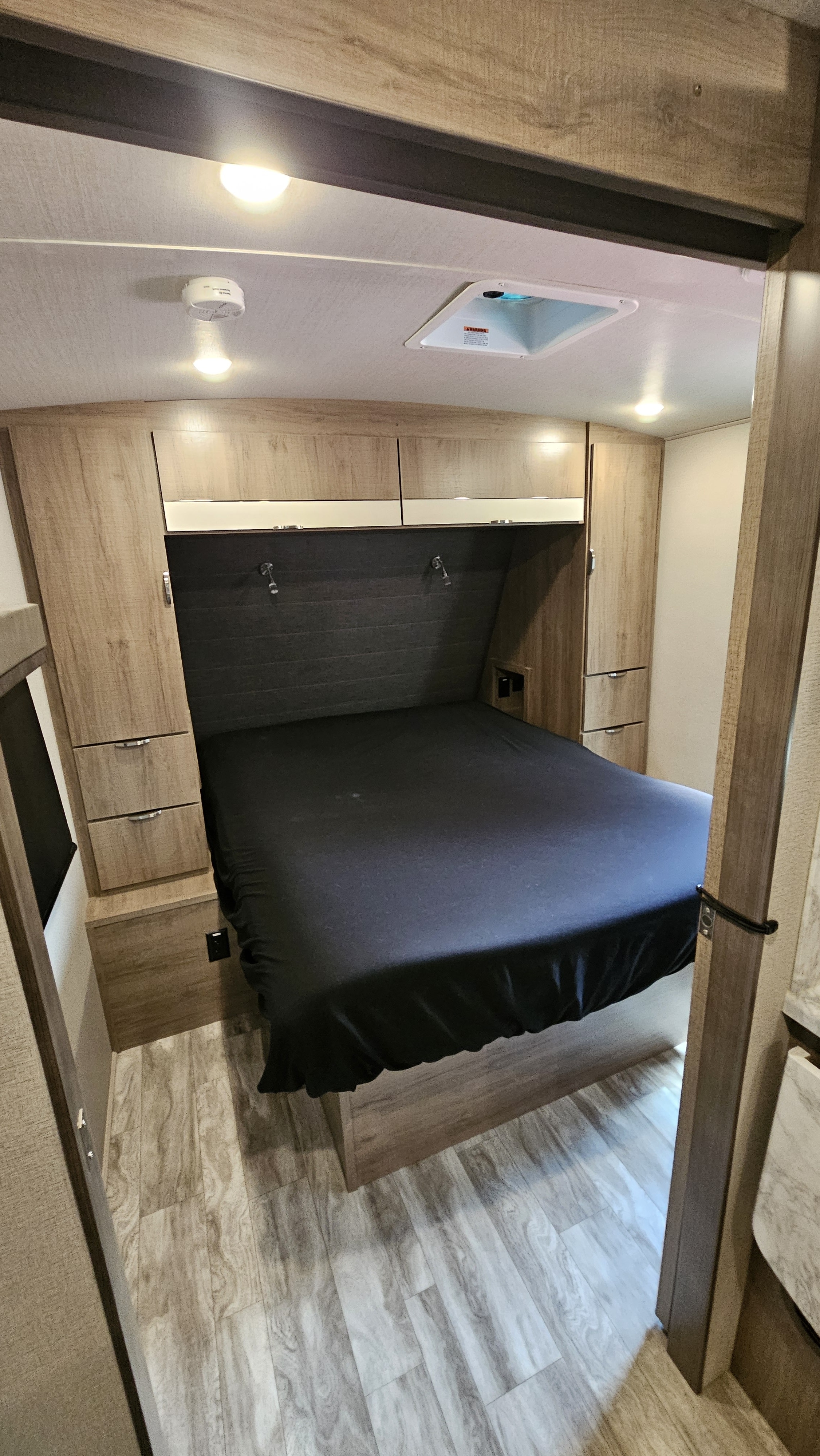 RV rental bedroom: cozy bed with built-in storage, bright overhead lights, and durable flooring for comfortable travel.. Grand Design Imagine 2021
