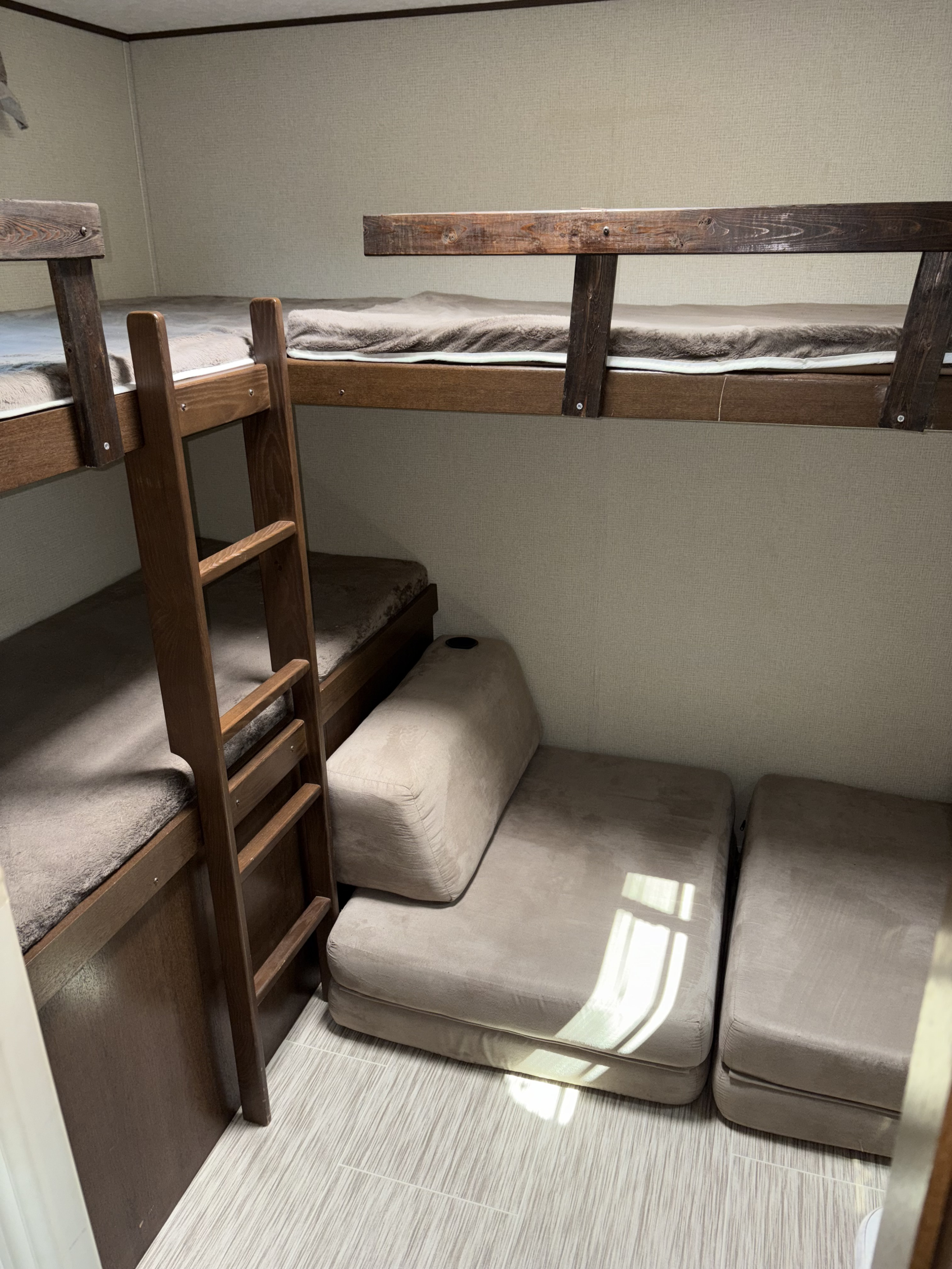 Cozy RV rental interior with bunk beds, a wooden ladder, and modular floor cushions for flexible sleeping/seating.. Avenger ATI 2018