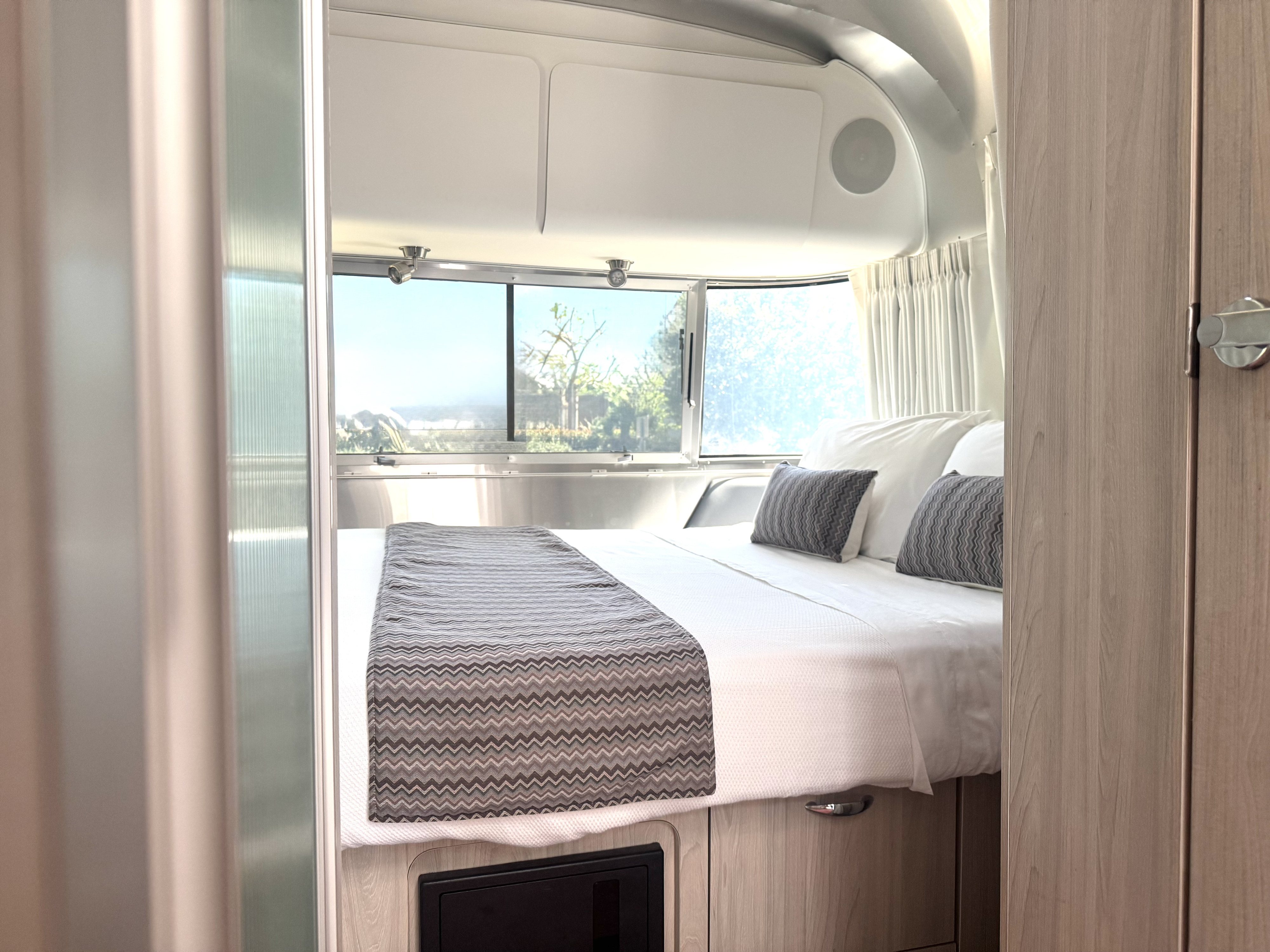 Bright RV rental bedroom: cozy bed, large windows, sleek interior. Perfect for your next adventure.. Airstream Globetrotter 2021