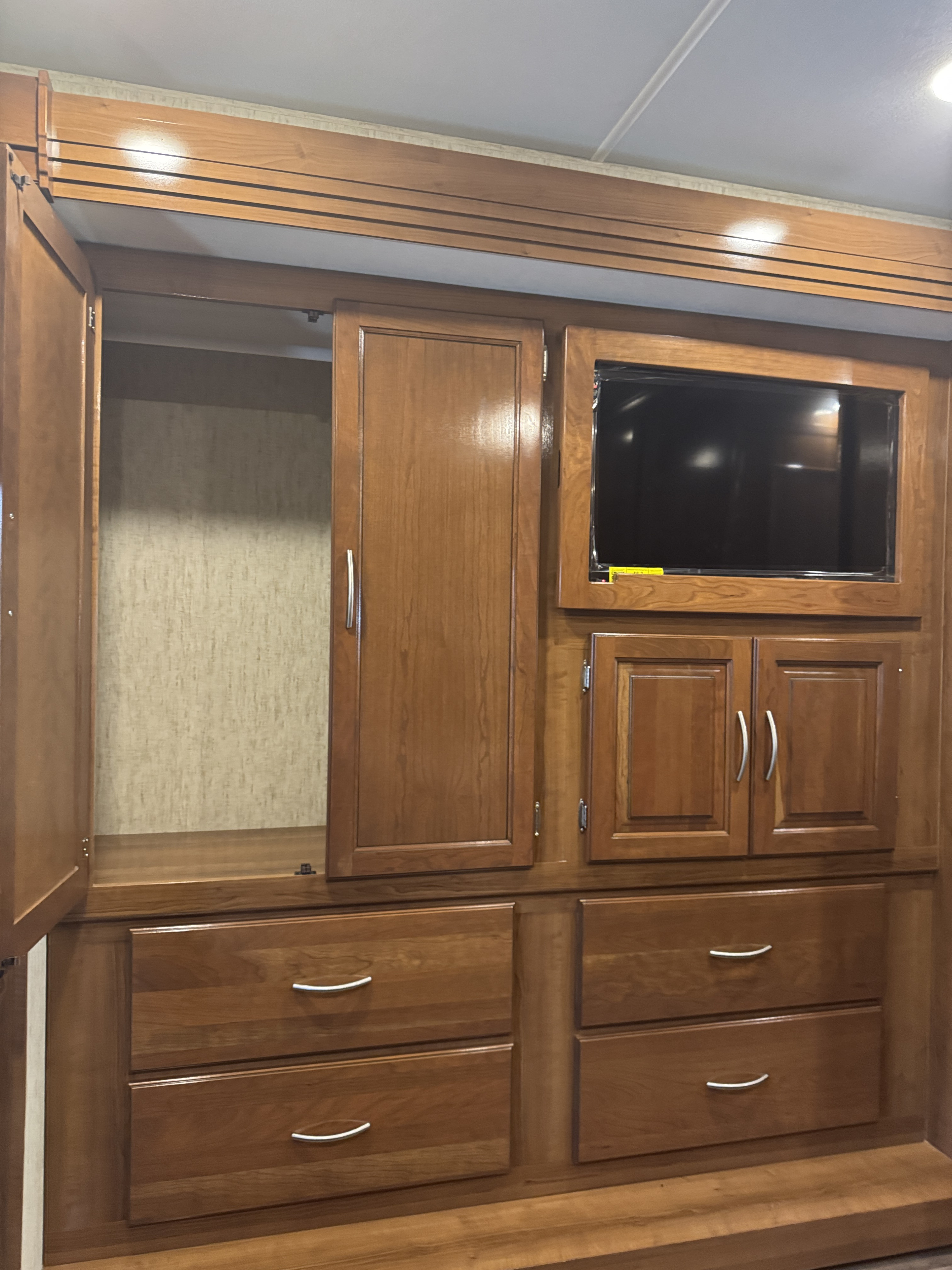 This RV rental interior features a sturdy wooden storage unit with an embedded TV, various cabinets, and curved-handle drawers.. Coachmen Forest River 2018