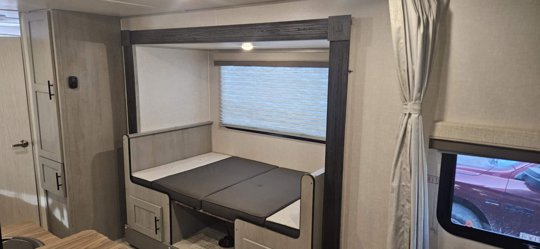 RV rental showcasing a versatile dinette area converted into a comfortable bed, complete with a window and storage.. Forest River Ibex Essentials+ Only 2024