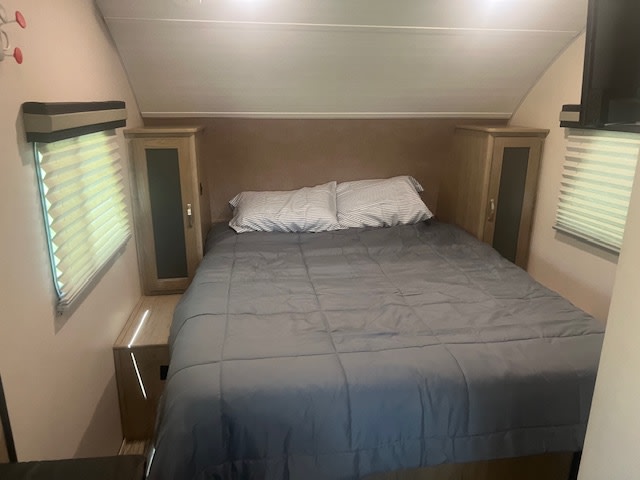 Cozy RV rental bedroom featuring a comfortable bed with a gray comforter, built-in cabinets, and windows with blinds.. R-Pod R-Pod Trailer 2020