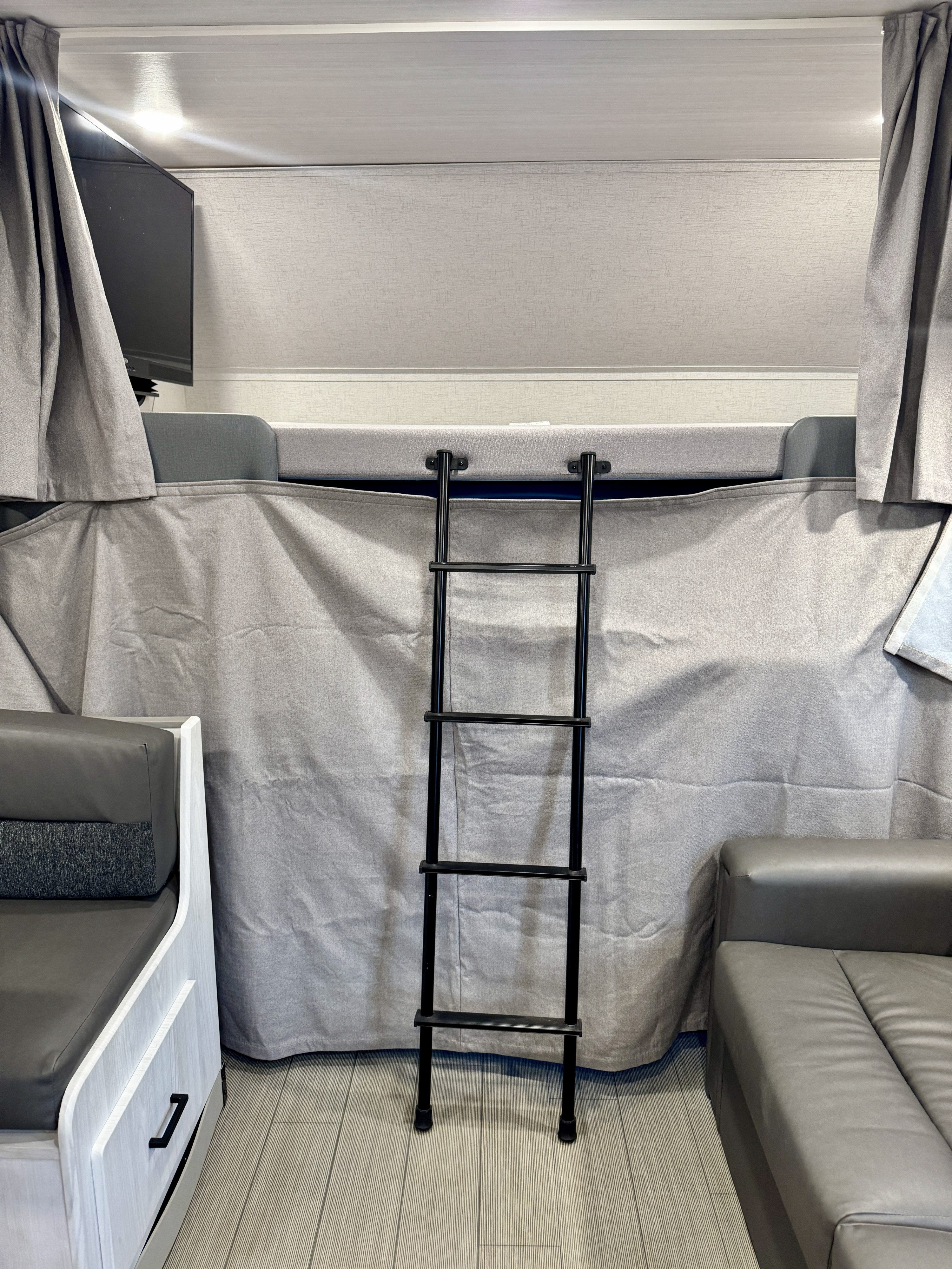 Interior of an RV rental showing a bunk bed with a ladder, privacy curtain, TV, and comfortable seating areas.. Entrada Entrada Motorhome 2022