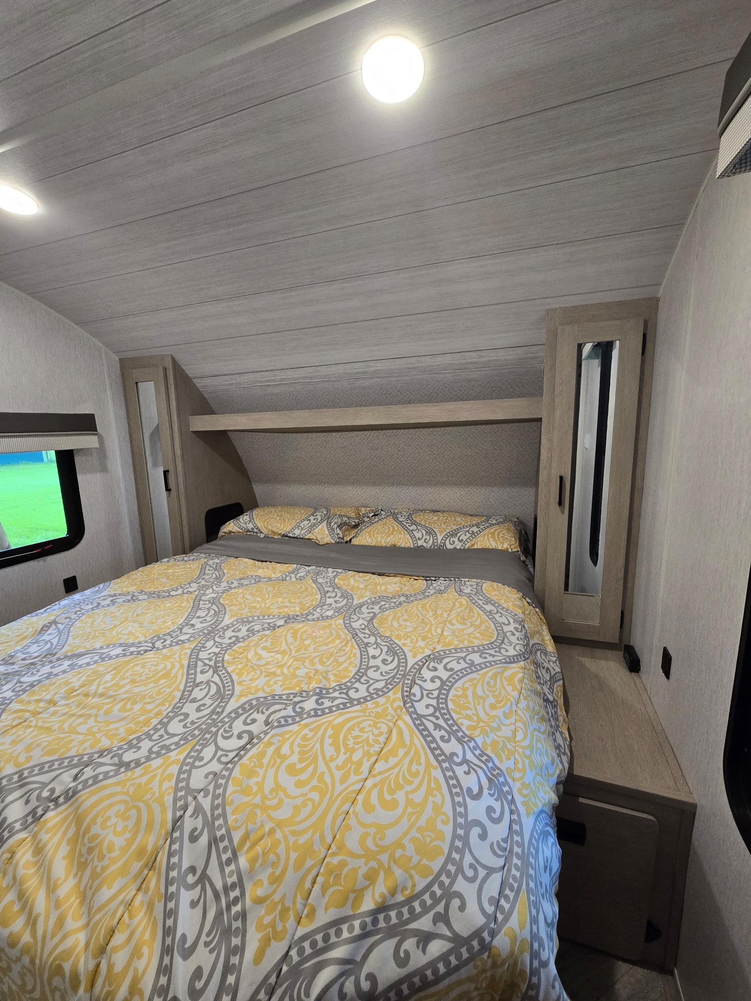 Cozy RV rental bedroom with a large bed, yellow and grey patterned bedding, mirrored cabinets, and ample overhead storage.. Forest River Salem Cruise Lite Platinum 2023
