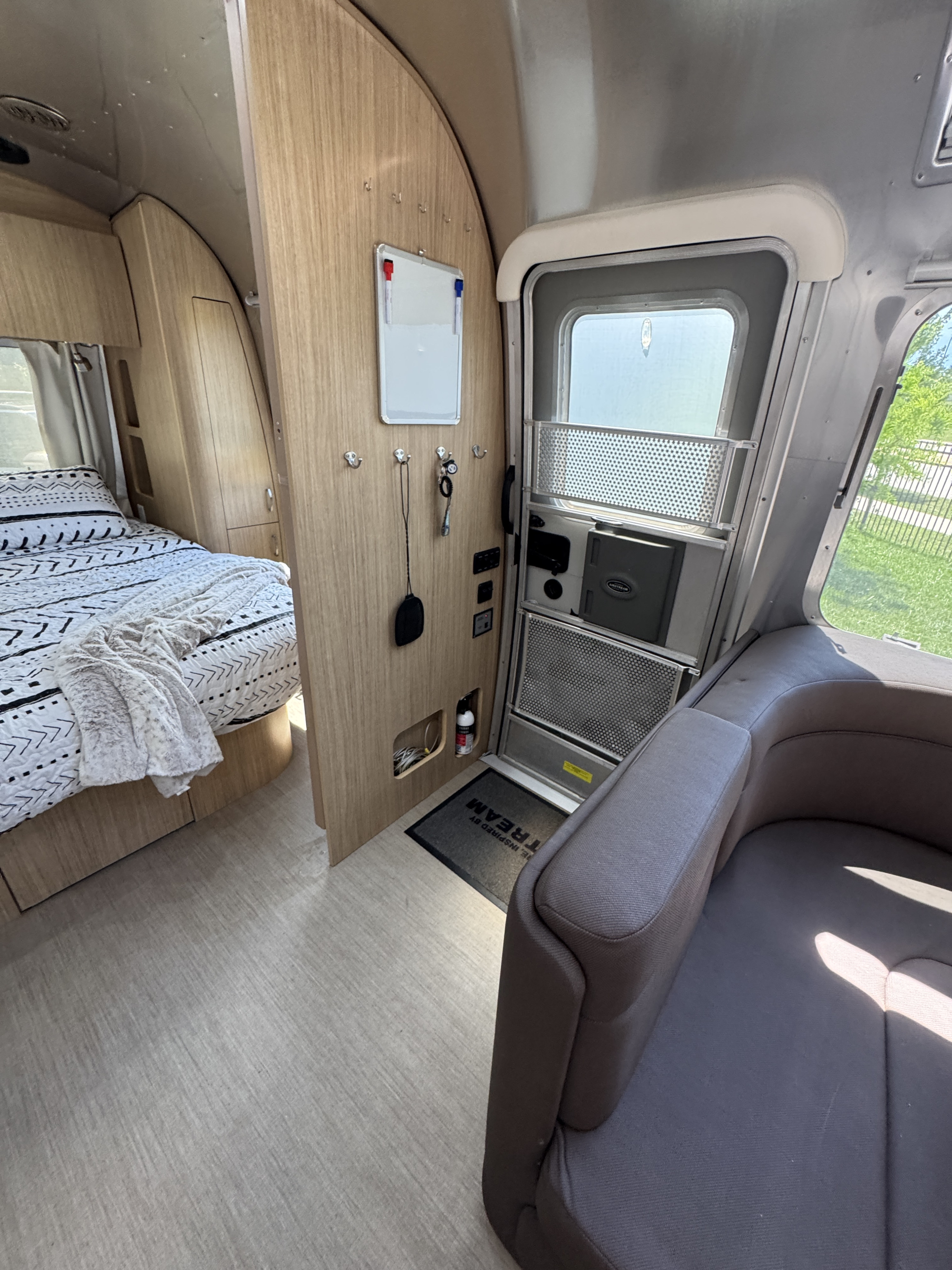 Explore this cozy RV rental interior featuring a bed, wood cabinetry, and comfortable seating, perfect for your next adventure.. Airstream Flying Cloud 2018