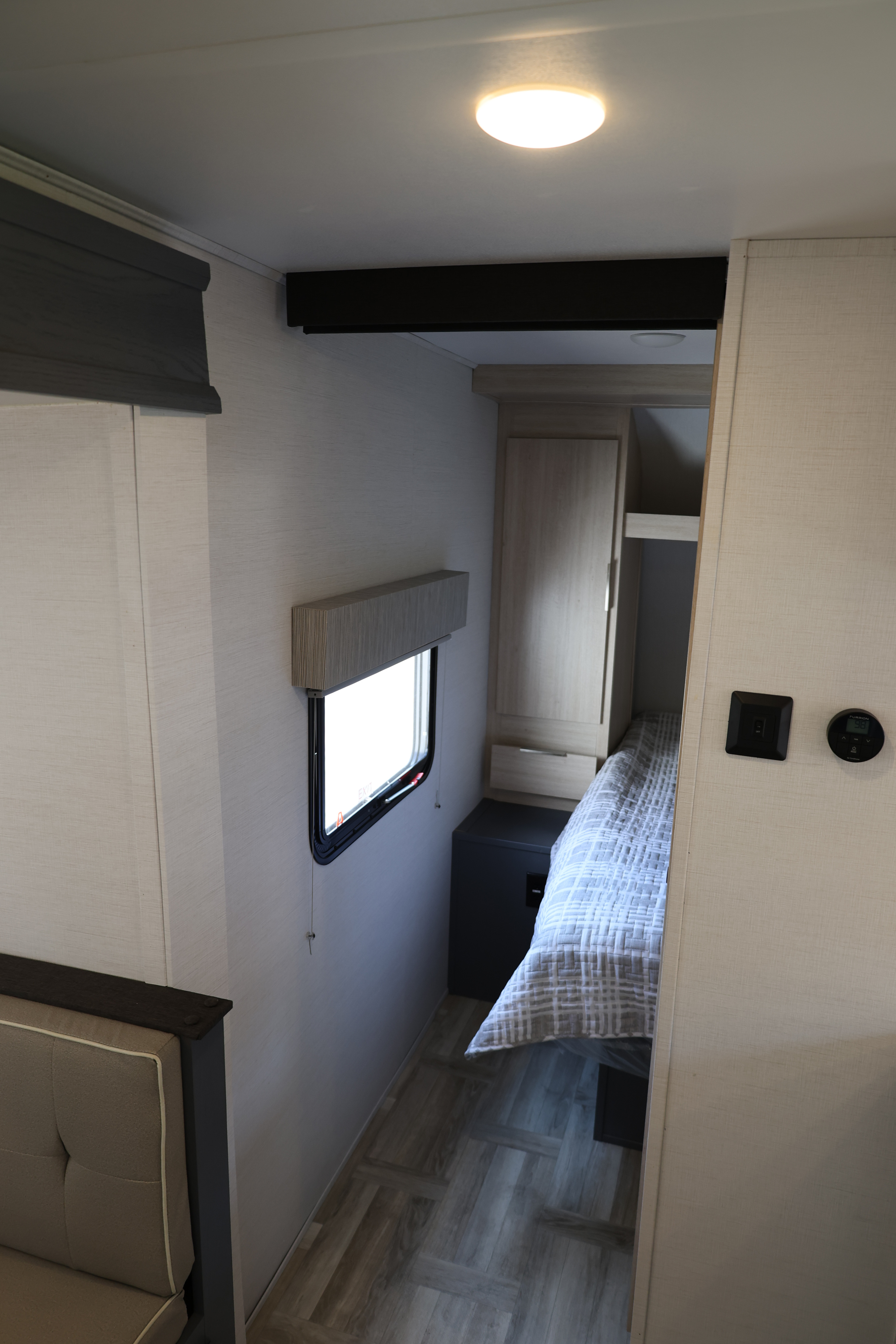Compact RV rental interior: bedroom with bed, window, cabinet, and adjacent sofa for comfortable travel.. Forest River Tracer 28BHS 2024