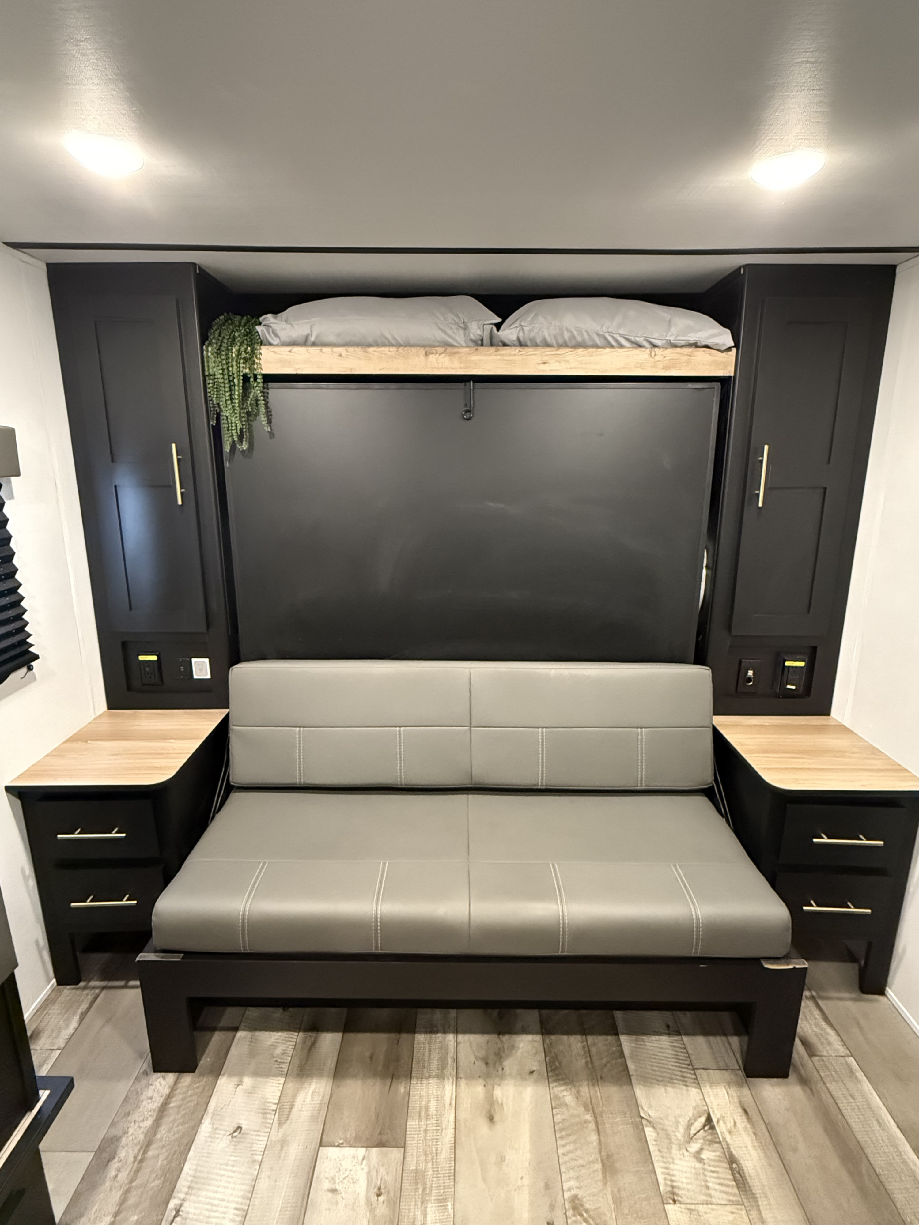 Stylish RV rental features a cozy, convertible sofa, a hidden wall bed, and modern dark wood cabinetry with lighting.. Keystone RV Springdale 2023