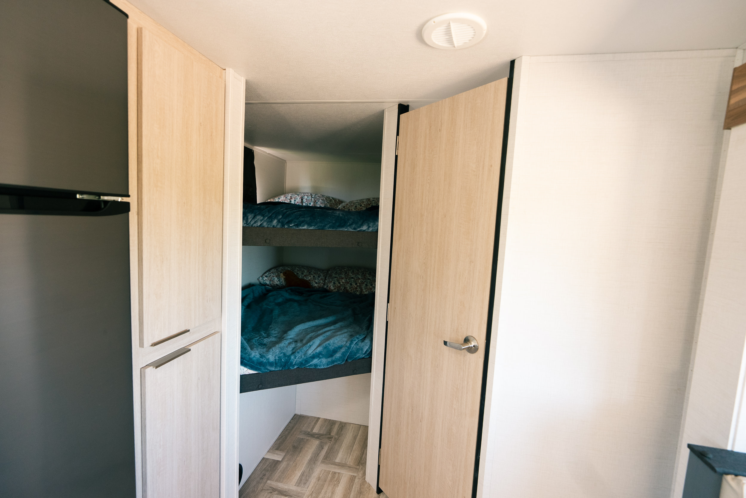 RV rental interior: light wood bunk beds, cabinetry, and a fridge on the left. Cozy sleeping quarters for travel.. Prime Time Tracer 270BHSLE 2024