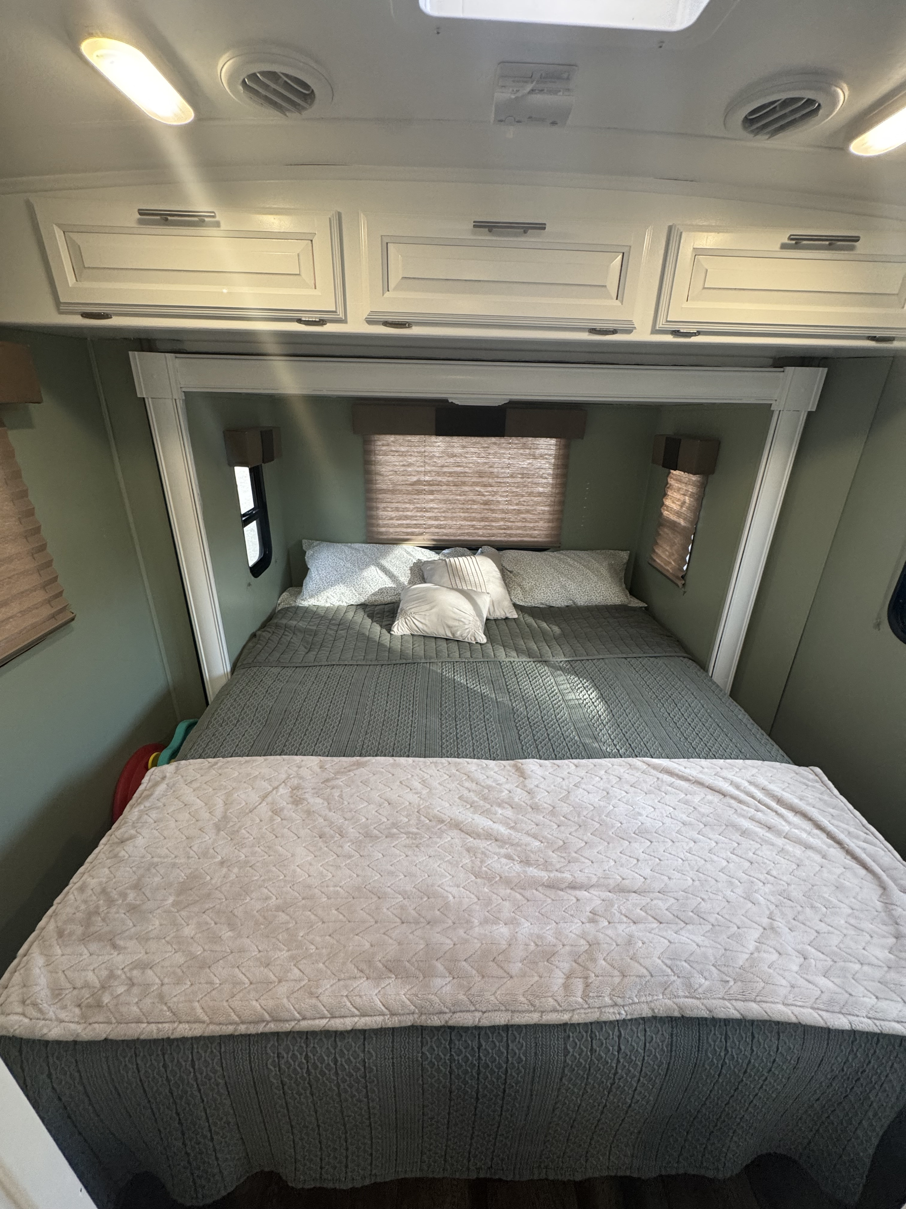 This RV rental bedroom features a comfy bed with grey and pink blankets, plus overhead storage and windows.. FR3 FR3 Motorhome 2016