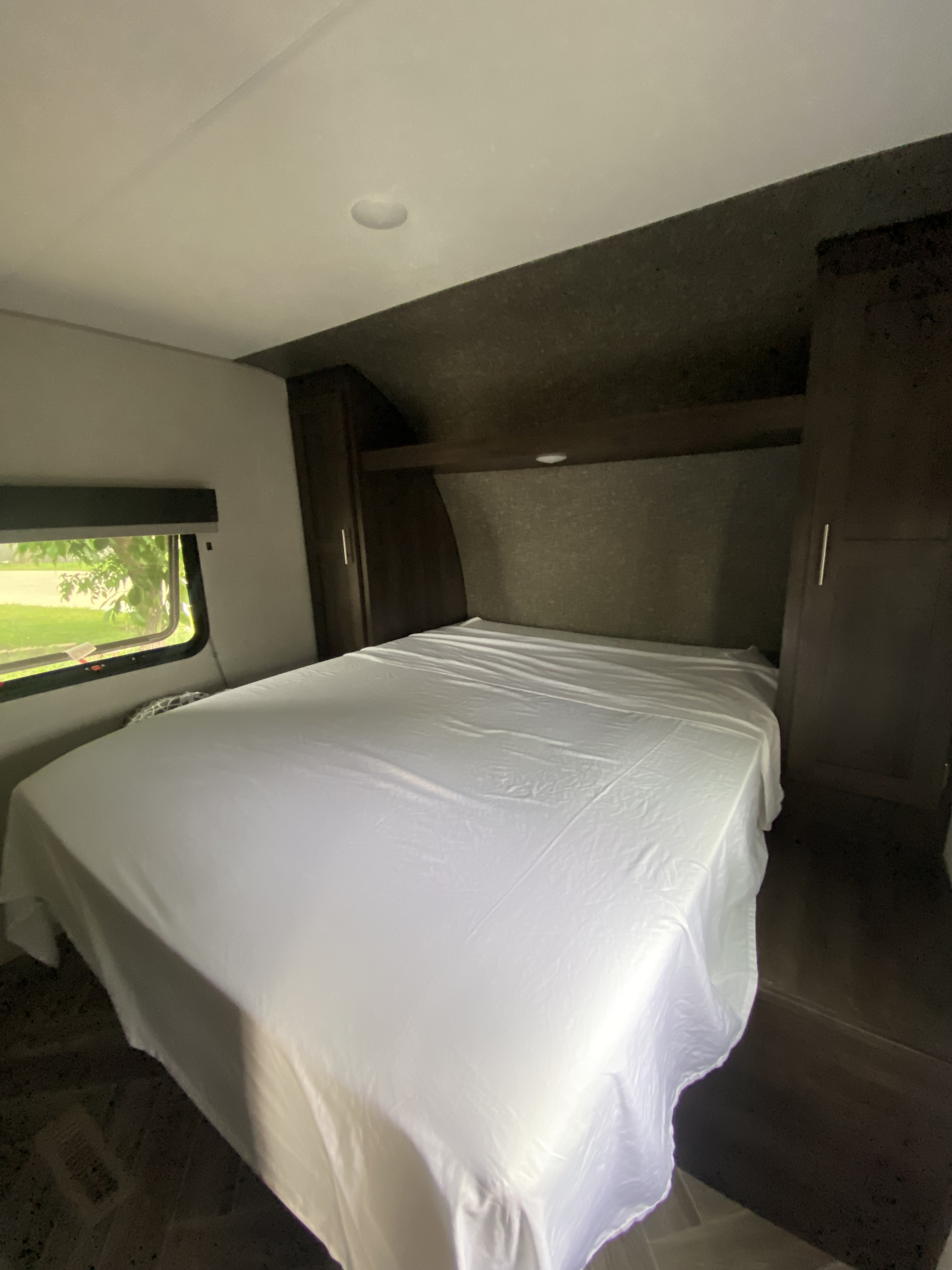 RV rental bedroom with white sheets, built-in cabinets, and a window. A cozy space for your next adventure.. Sportsmen SE 2020
