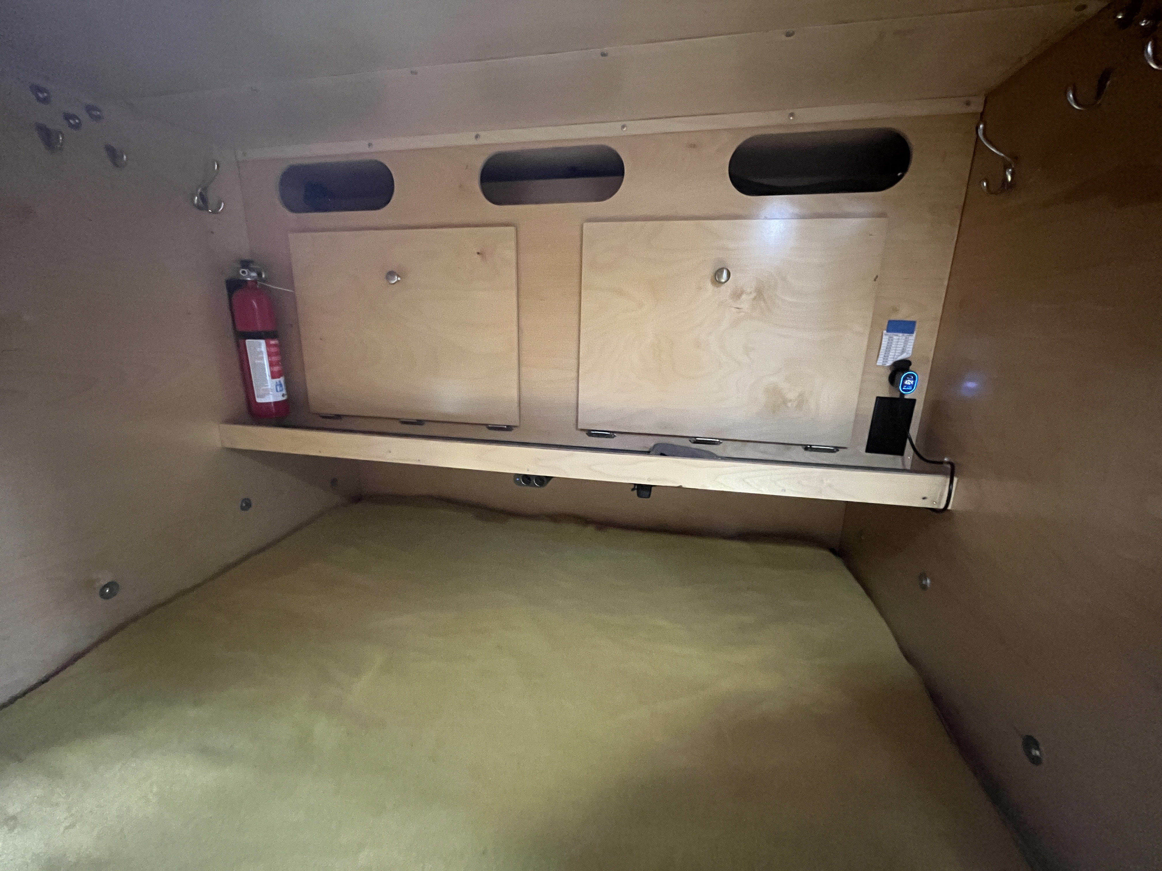 RV rental interior: Compact sleeping area with mattress, storage, fire extinguisher, and power access.. Teardrops NW Ranger 2019