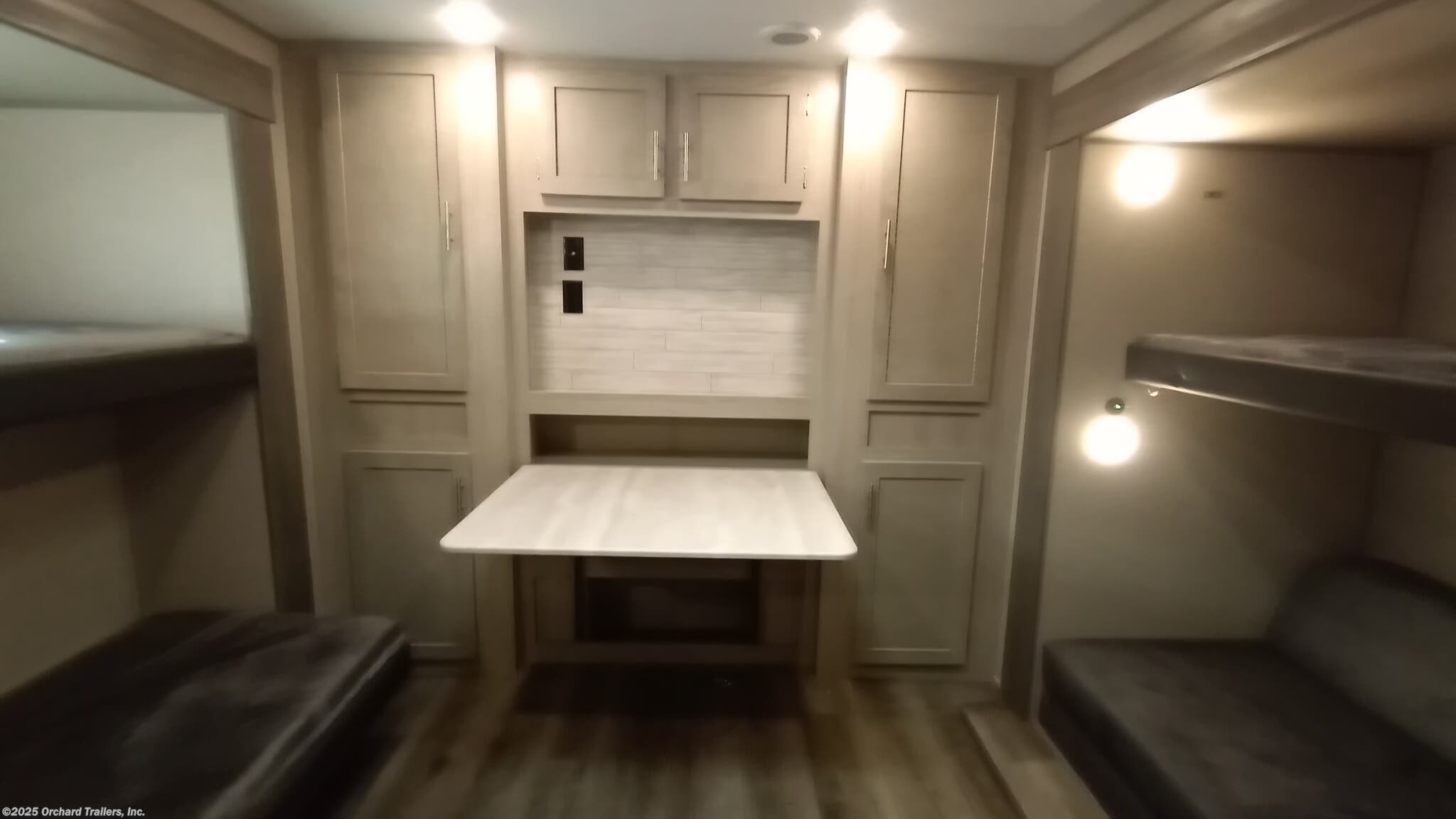 Inside this **RV rental**: bunk beds line both walls, centering a fold-down dinette with overhead cabinets. Compact comfort.. Coachmen Catalina 2023