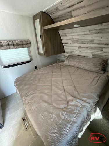 Inside this RV rental, find a comfortable bedroom featuring a bed, rustic wall paneling, and practical overhead storage.. Forest River Palomino Puma XLE 2020