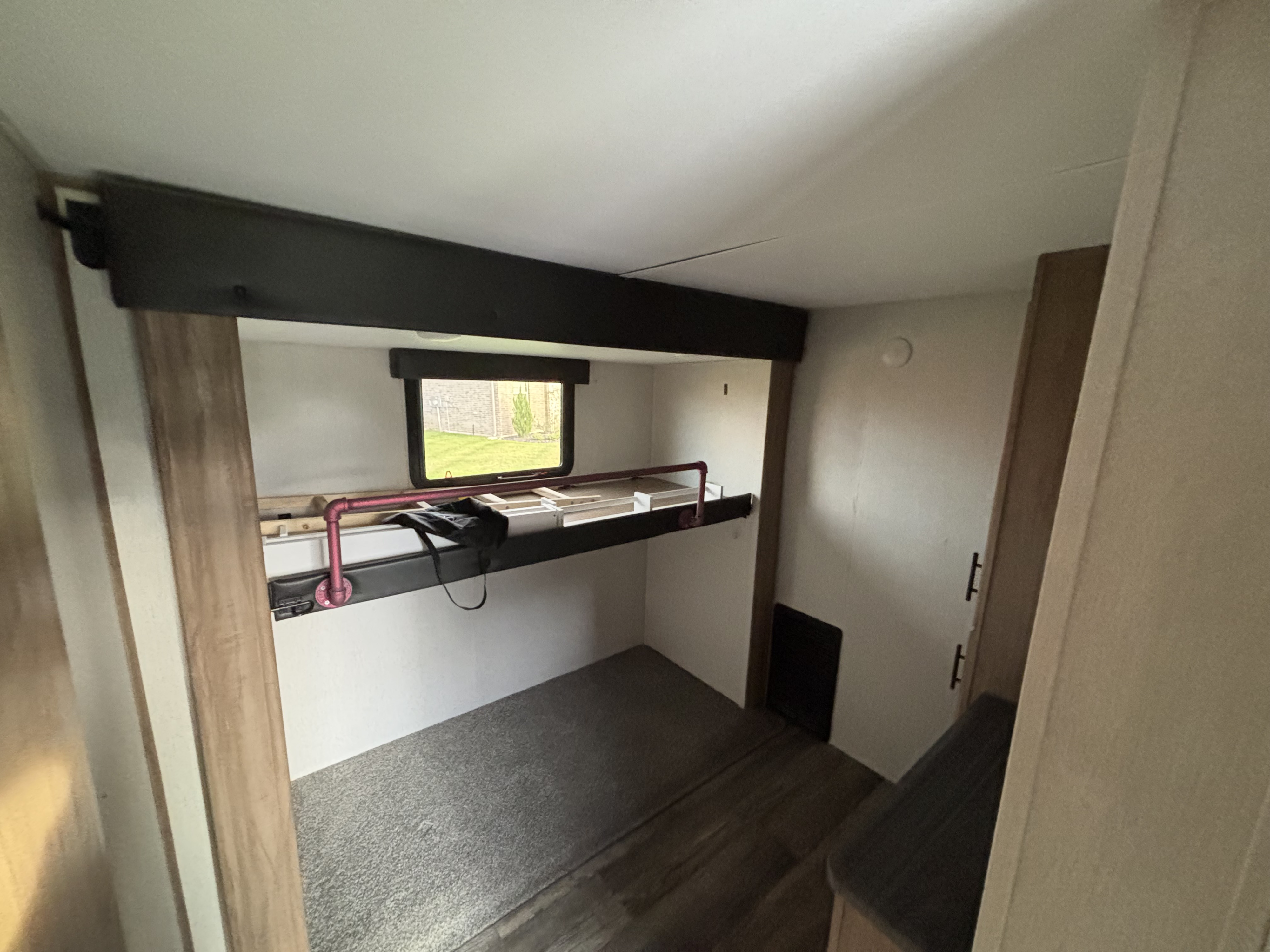 RV rental interior: bunk bed area with window, carpeted floor, and a distinct red pipe railing.. Forest River Cherokee Arctic Wolf 2023