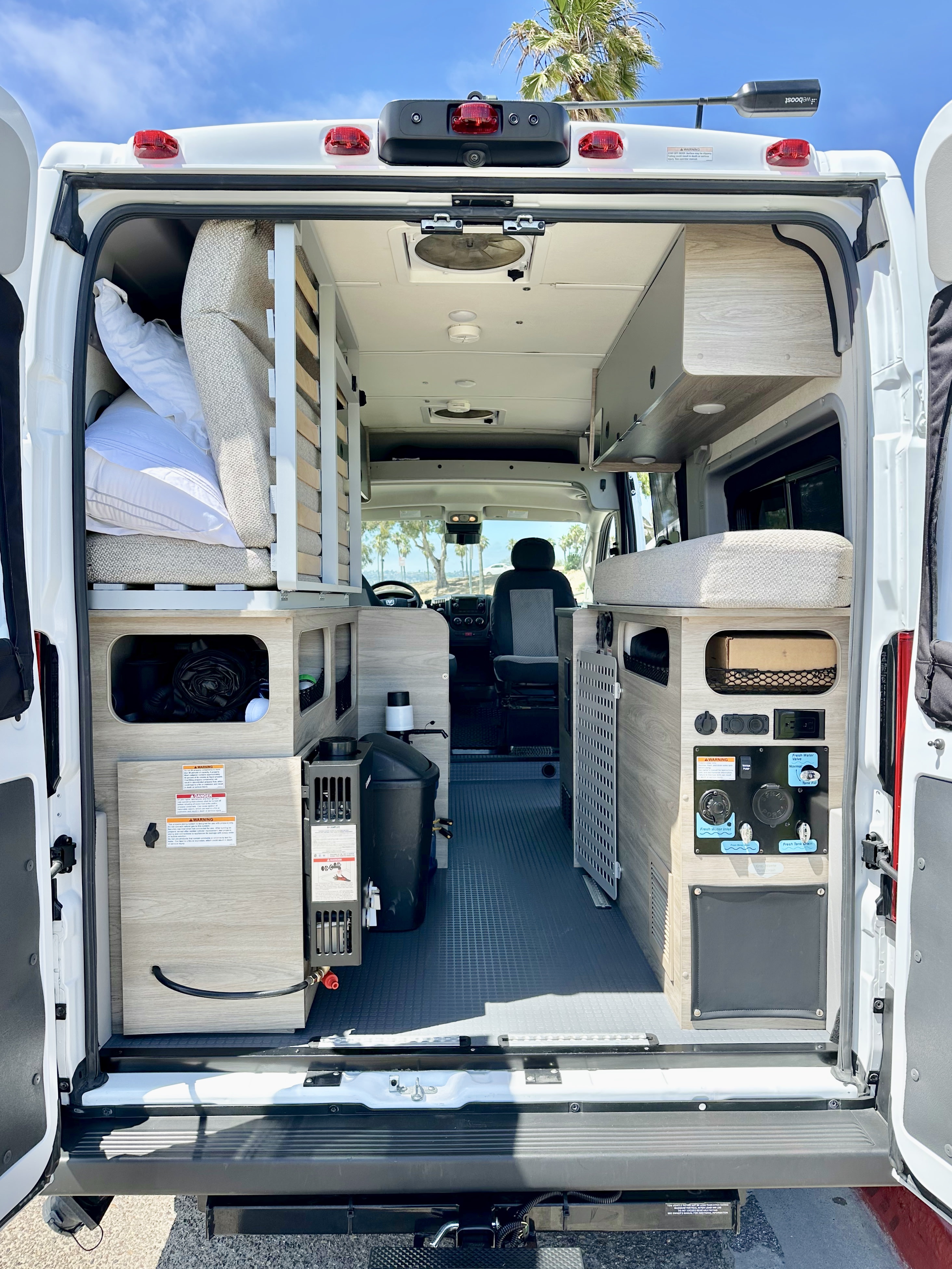 View from the rear of an **rv rental** camper van, showcasing custom interior layout with beds, storage, and water system.. Winnebago Solis Pocket 2022