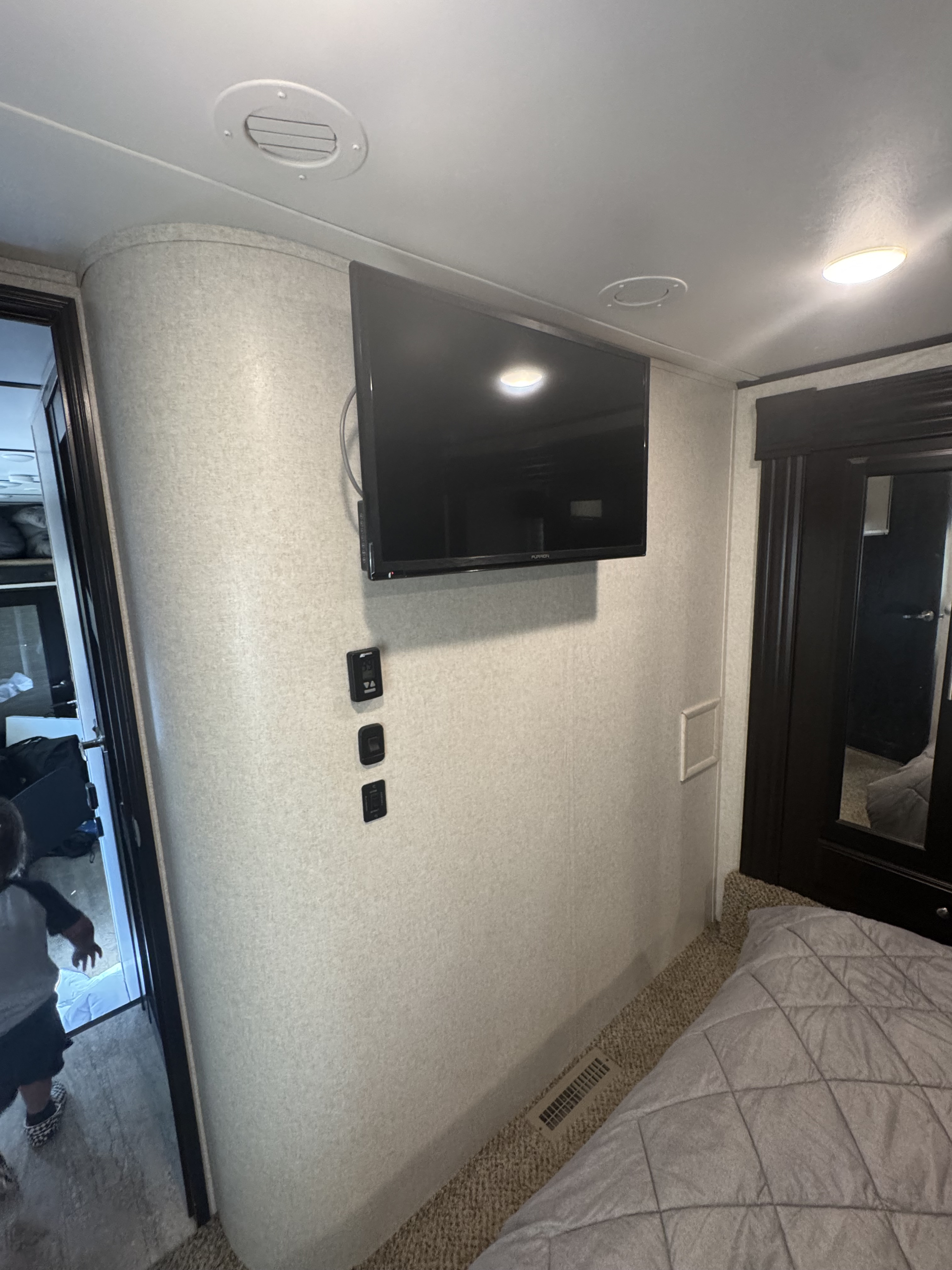 Cozy RV rental bedroom features wall-mounted TV, control panel, ceiling vents, and a comfortable bed.. Jayco Seismic Toy Hauler 2017